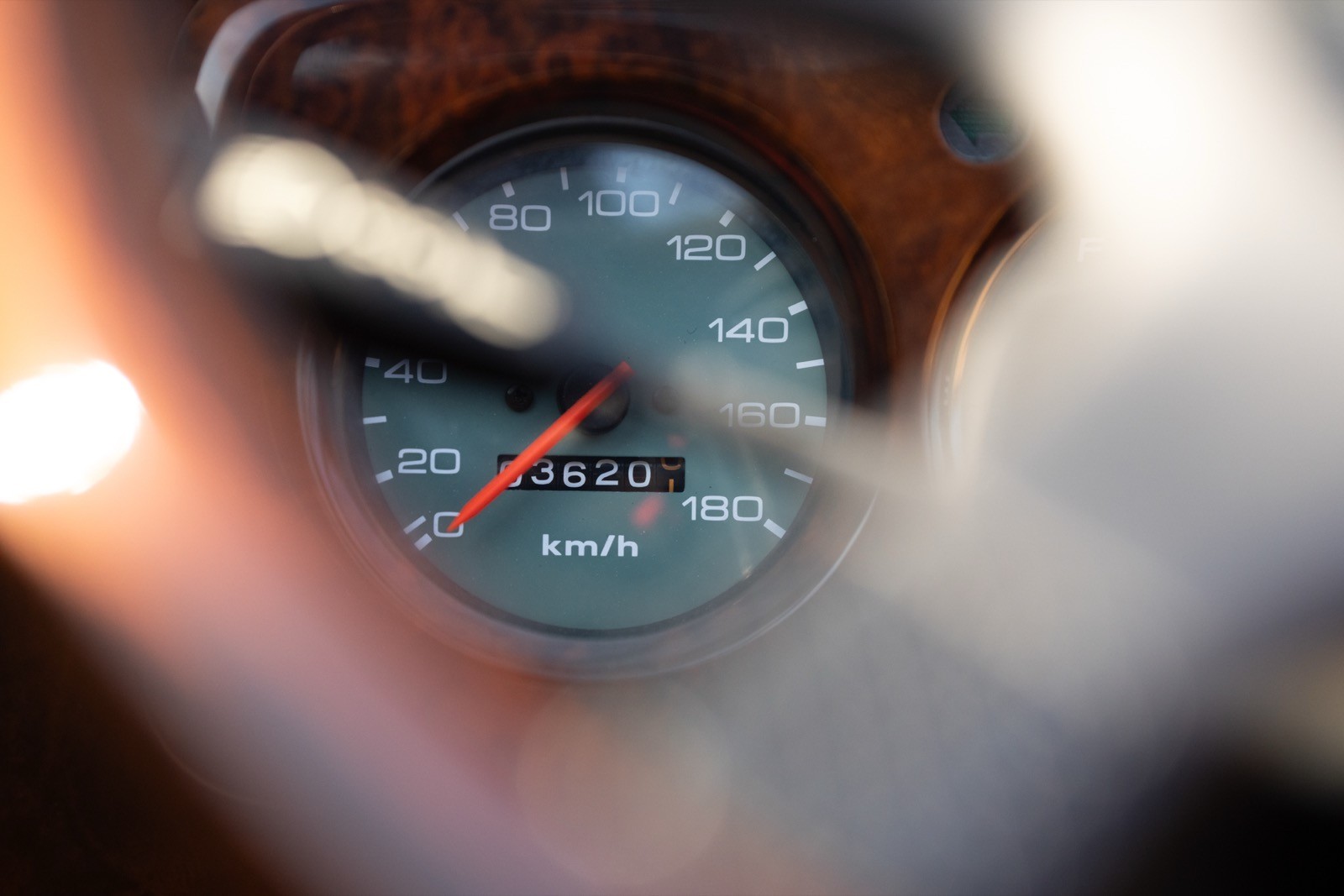 Close-up of a hand holding a gauge with a needle indicating measurement on a blue dial.
