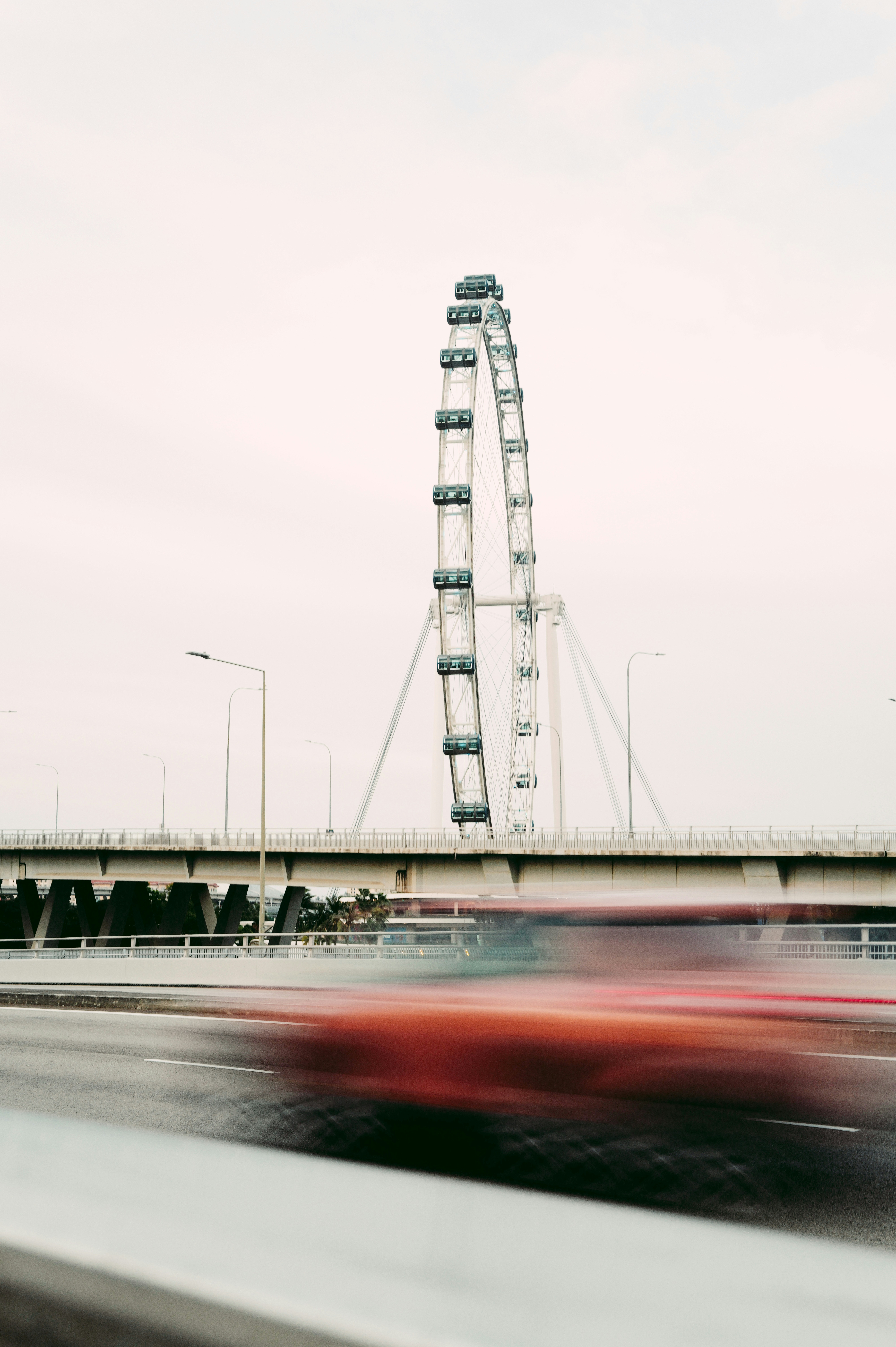 Ferris wheel with blurred traffic on a bridge