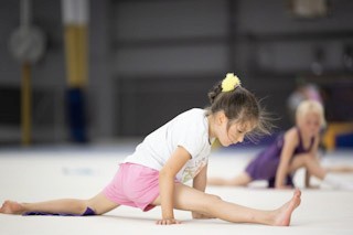 Two girls practicing their split at a preschool gymnastics class