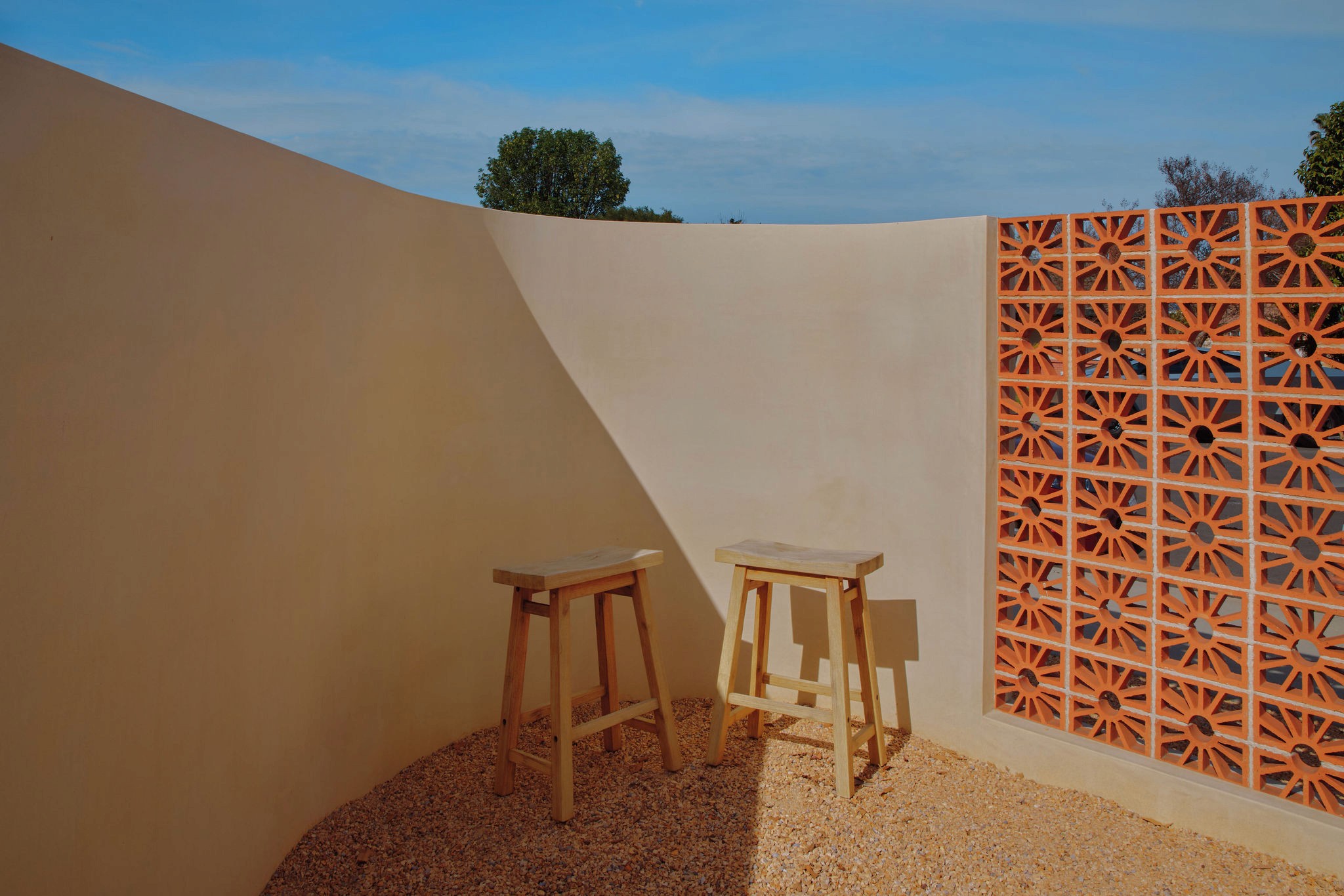 A crow perched on a pipe against an orange sky.