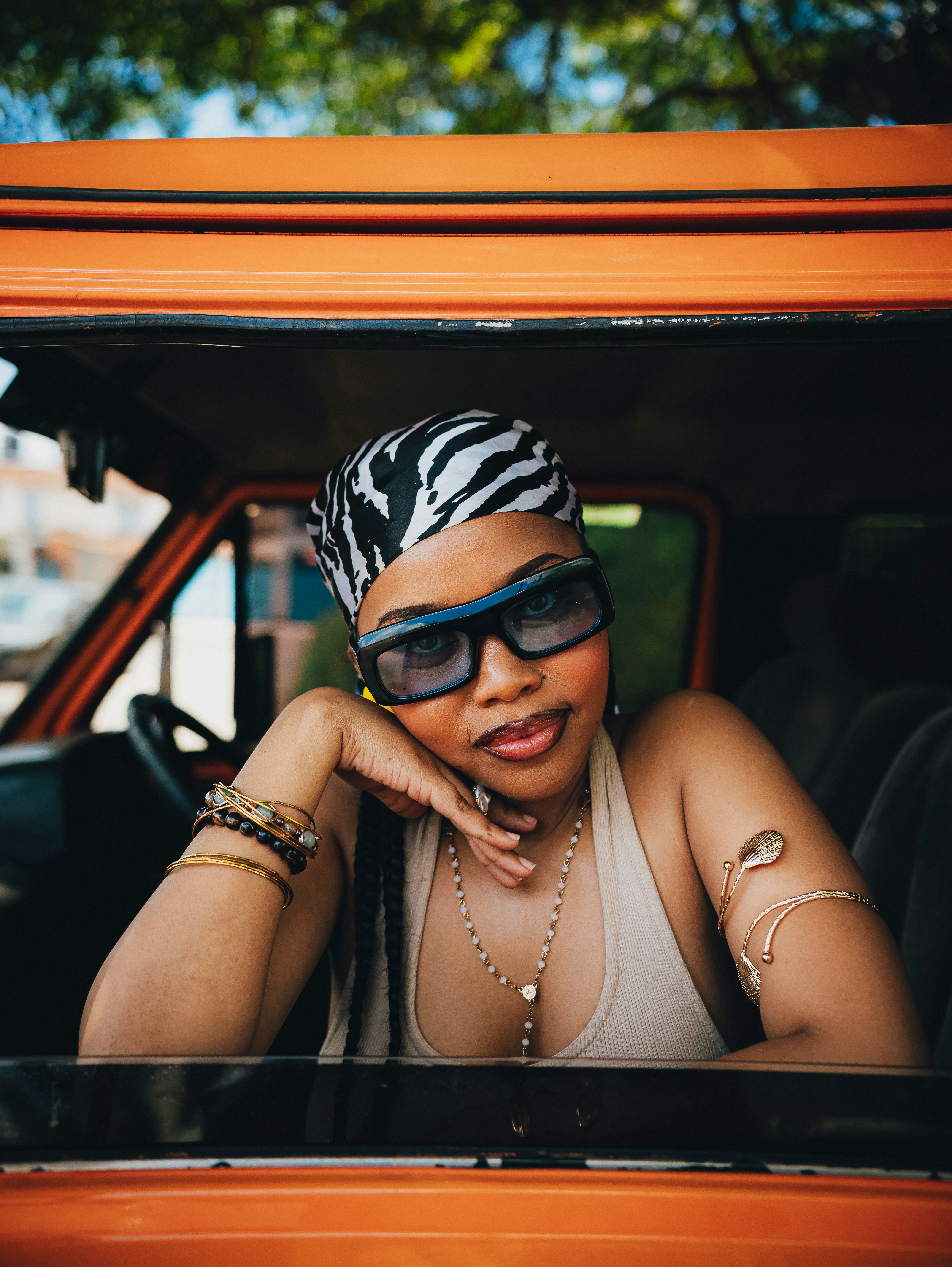 Woman with sunglasses and headscarf in orange vehicle