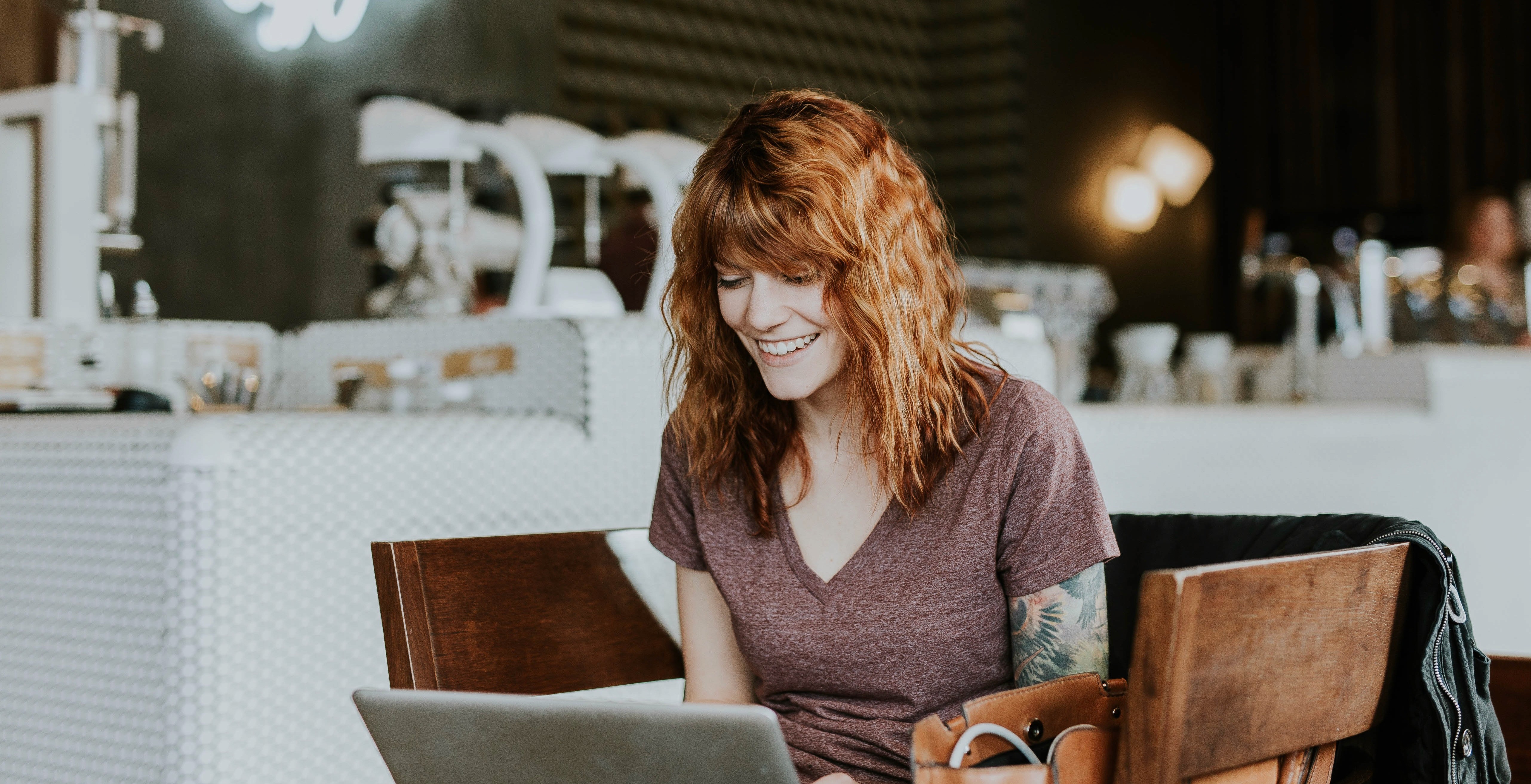 Woman in purple shirt typing in a restaurant and enjoying remote work benefits