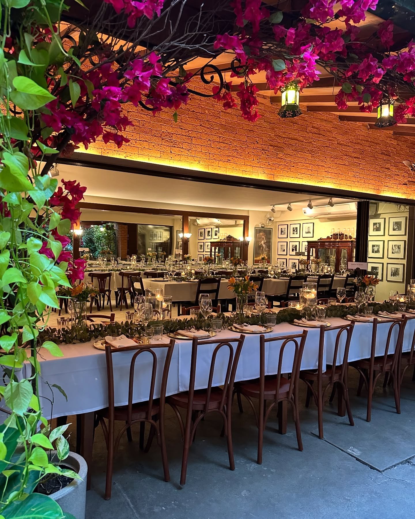 A beautifully set dining table with white tablecloth, cutlery, and fresh greenery in a cozy, well-lit space.