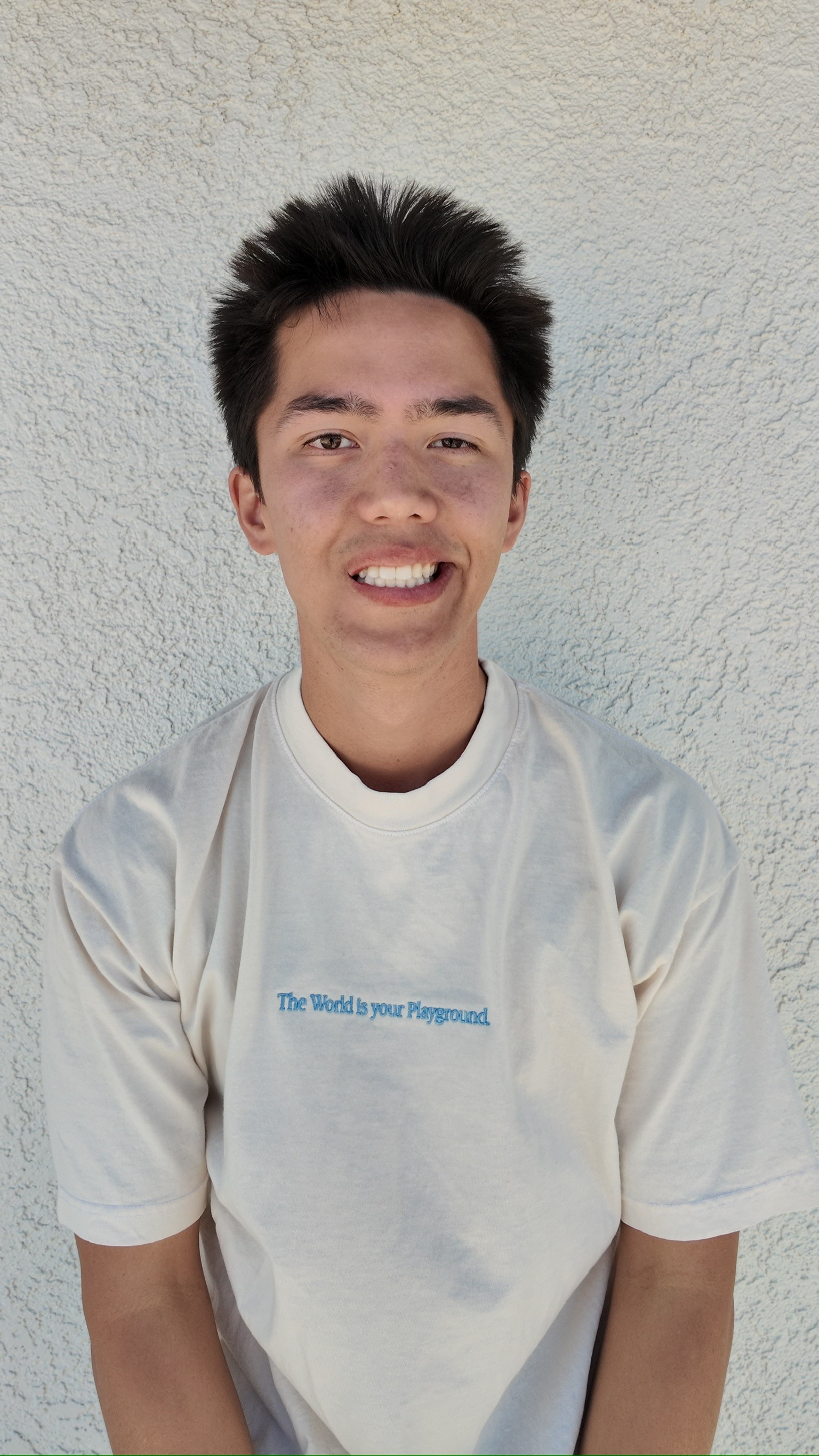 Portrait of Tyler Morris, Chief of Staff at Playkit, smiling in front of a beige wall and wearing a white collared shirt.