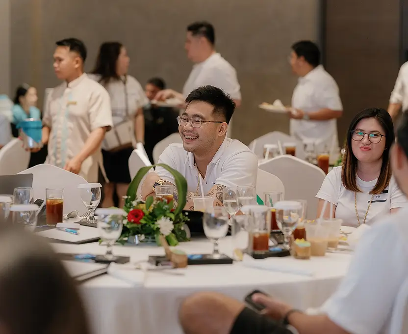 HighCall Virtual Assistants team members smiling and enjoying drinks around a decorated banquet table during a company gathering.