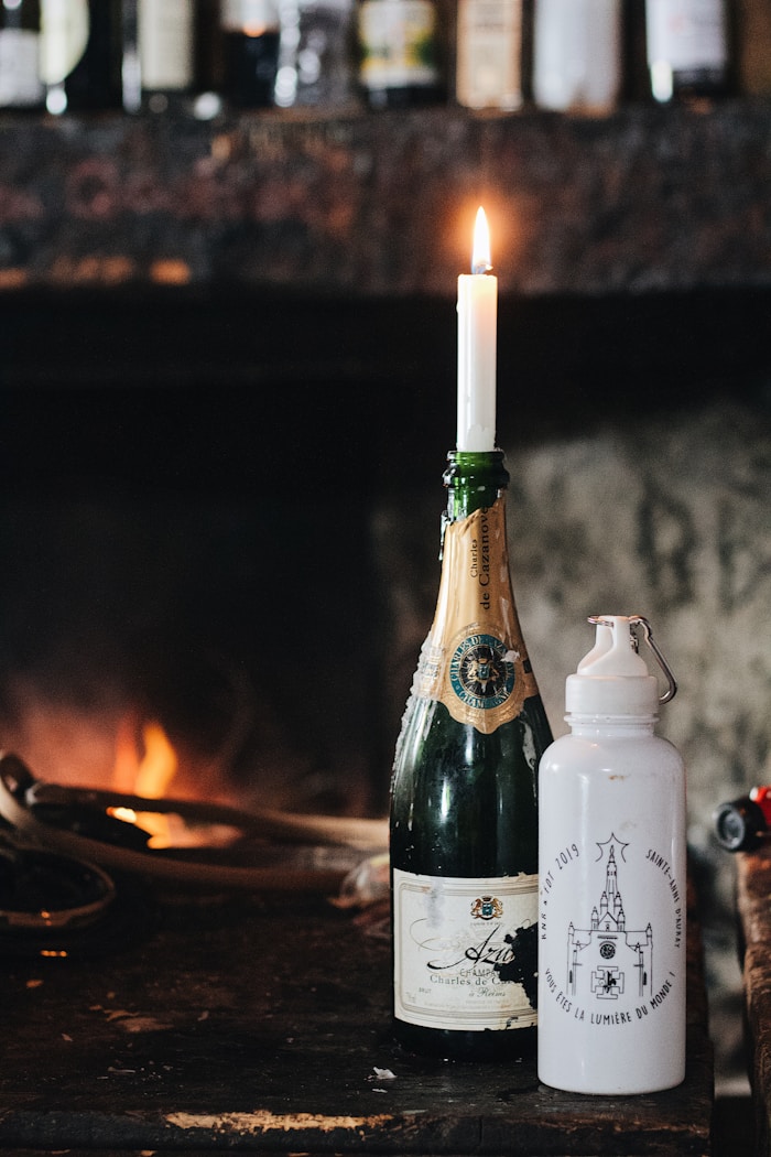 Vintage champagne bottle repurposed as a candle holder beside a fireplace