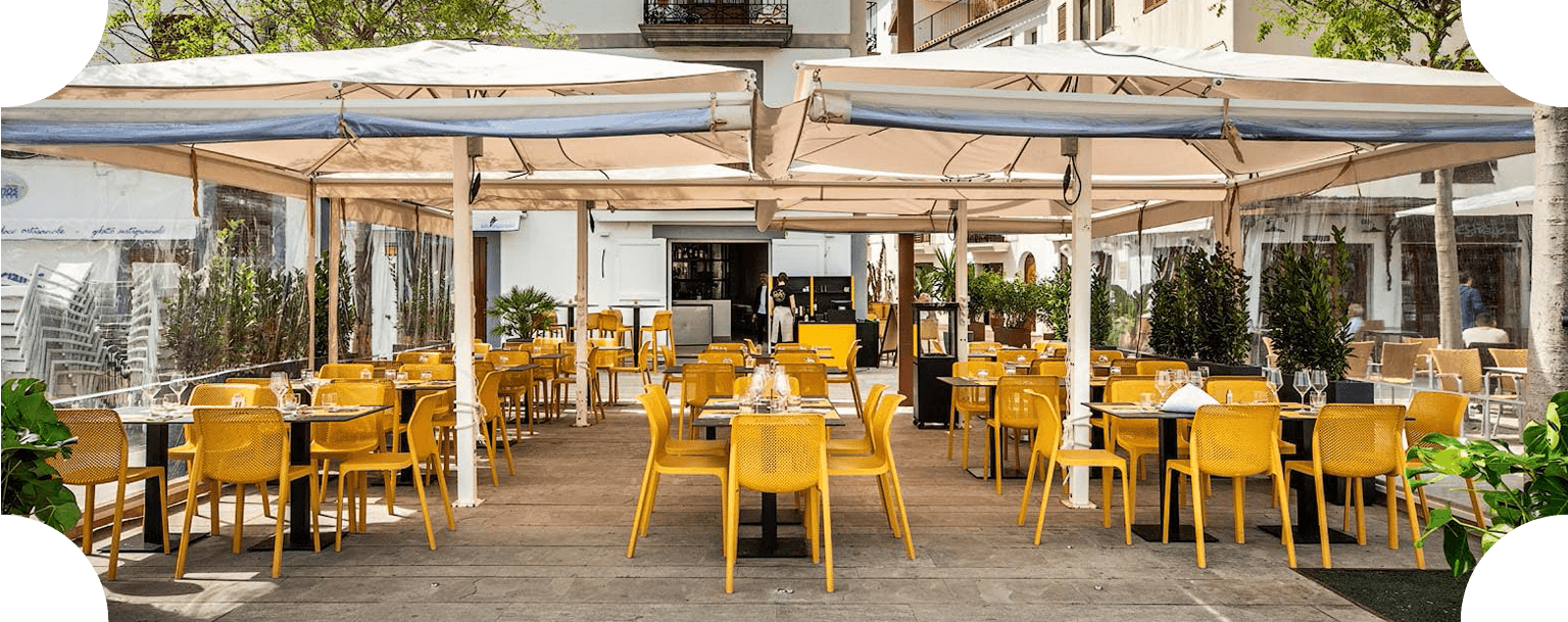 Terraza exterior de Casa Francesco con sillas amarillas y mesas bajo grandes toldos color crema.