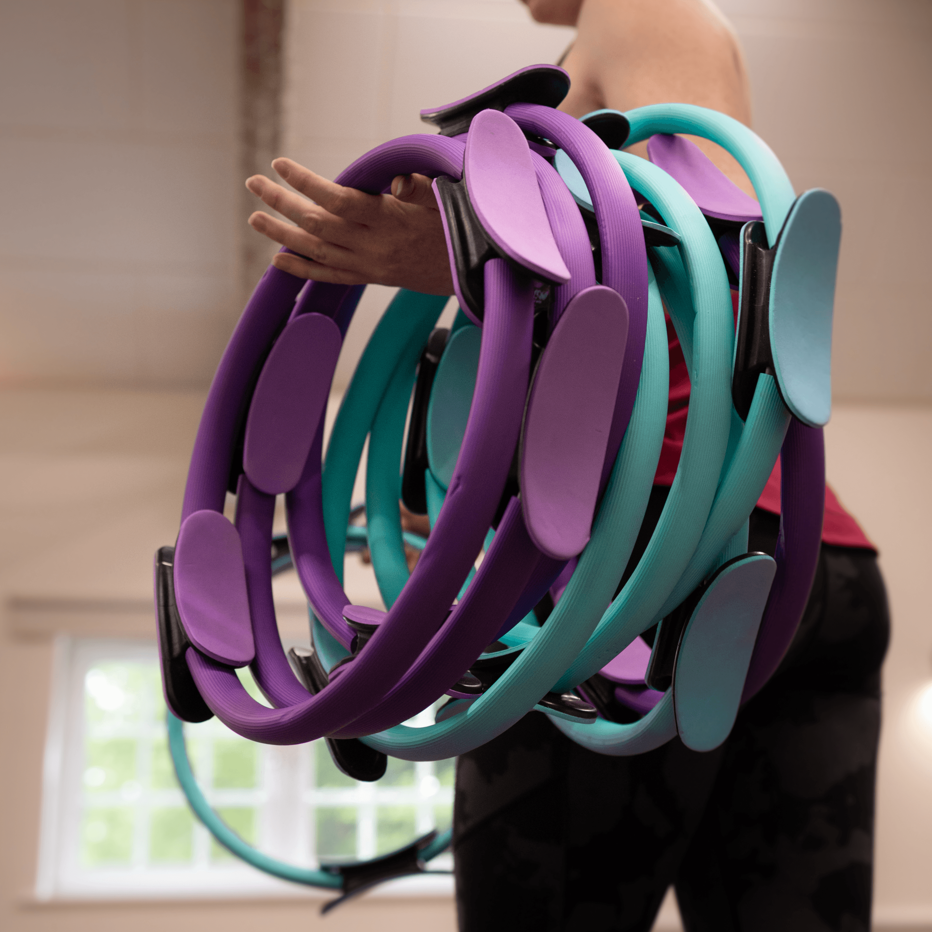 A woman holding pilates rings around her arm in a studio.