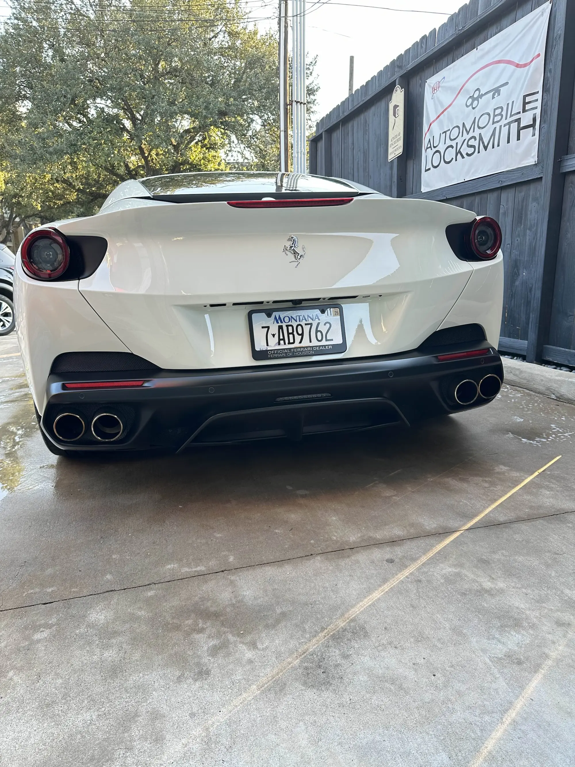 Rear view of a white Ferrari luxury car parked at a Houston, TX detailing facility following an intensive exterior cleaning and exhaust tip polishing.