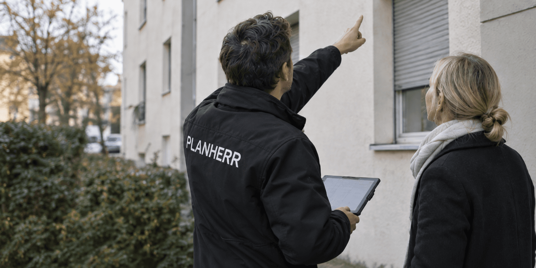 PLANHERR Mitarbeiter bespricht ein Bestandsgebäude mit einer Eigentümerin vor Ort.