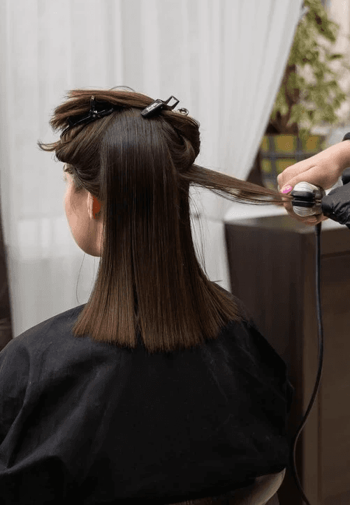 Mujer con cabello oscuro castaño y de longitud media siendo alisado en Peluquería Carlos y Hugo Spa en Arequipa