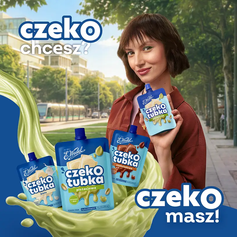Kobieta trzymająca tubkę pistacjowego kremu Wedel na tle miasta
