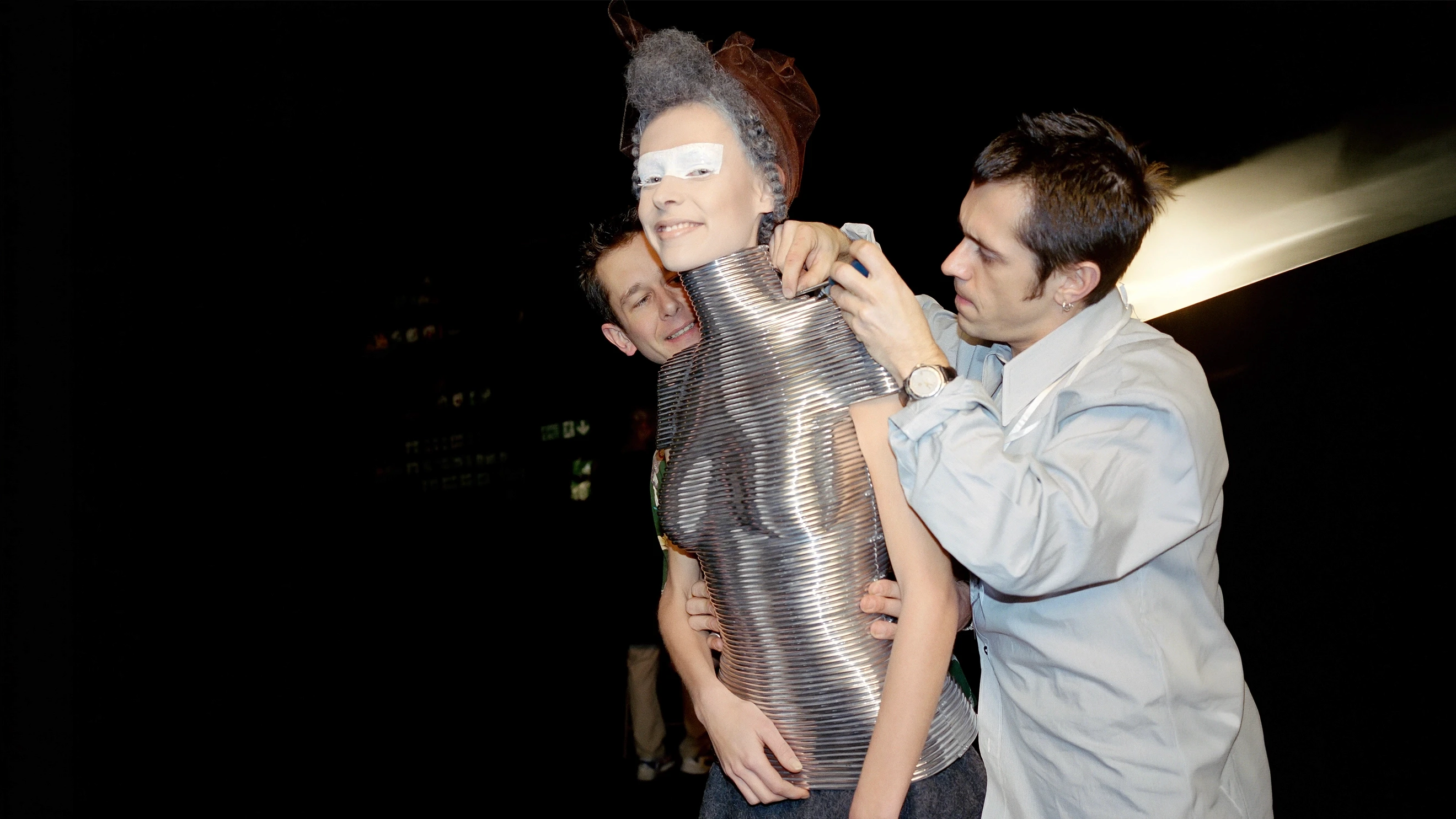 Backstage view of a model being fitted into the iconic silver metal Coiled Corset, a couture body armour collaboration between jeweller Shaun Leane and designer Alexander McQueen.