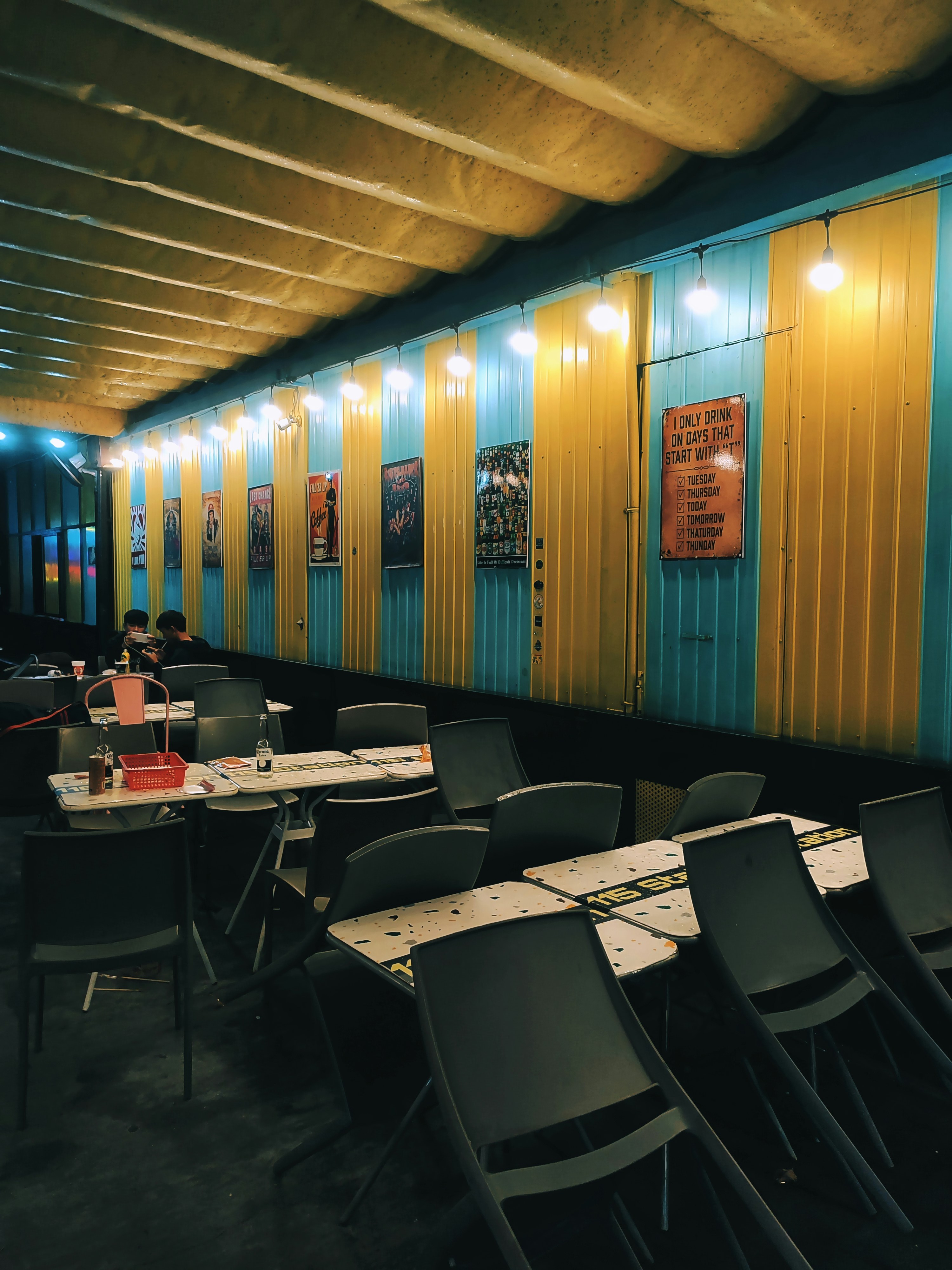 a dining area with tables and chairs in front of a yellow and blue wall