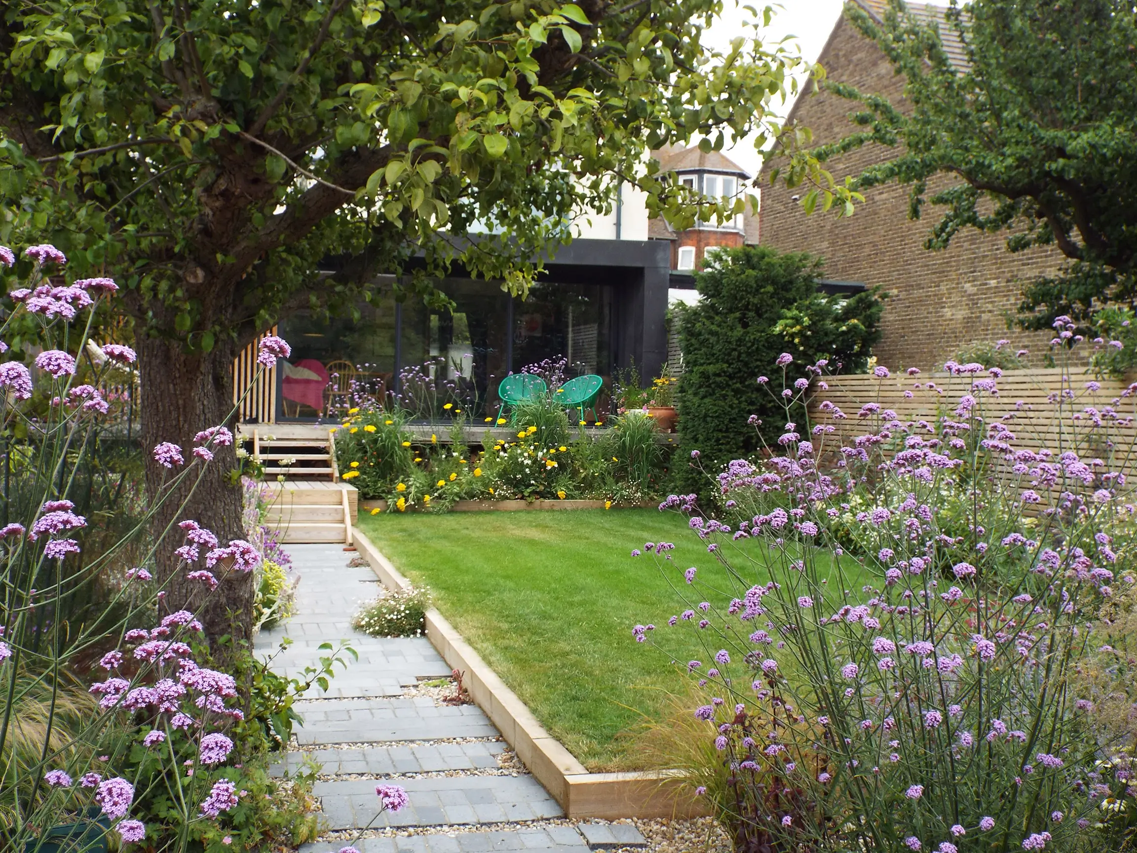A serene garden scene featuring a path, greenery, and flowers, creating a tranquil outdoor atmosphere.