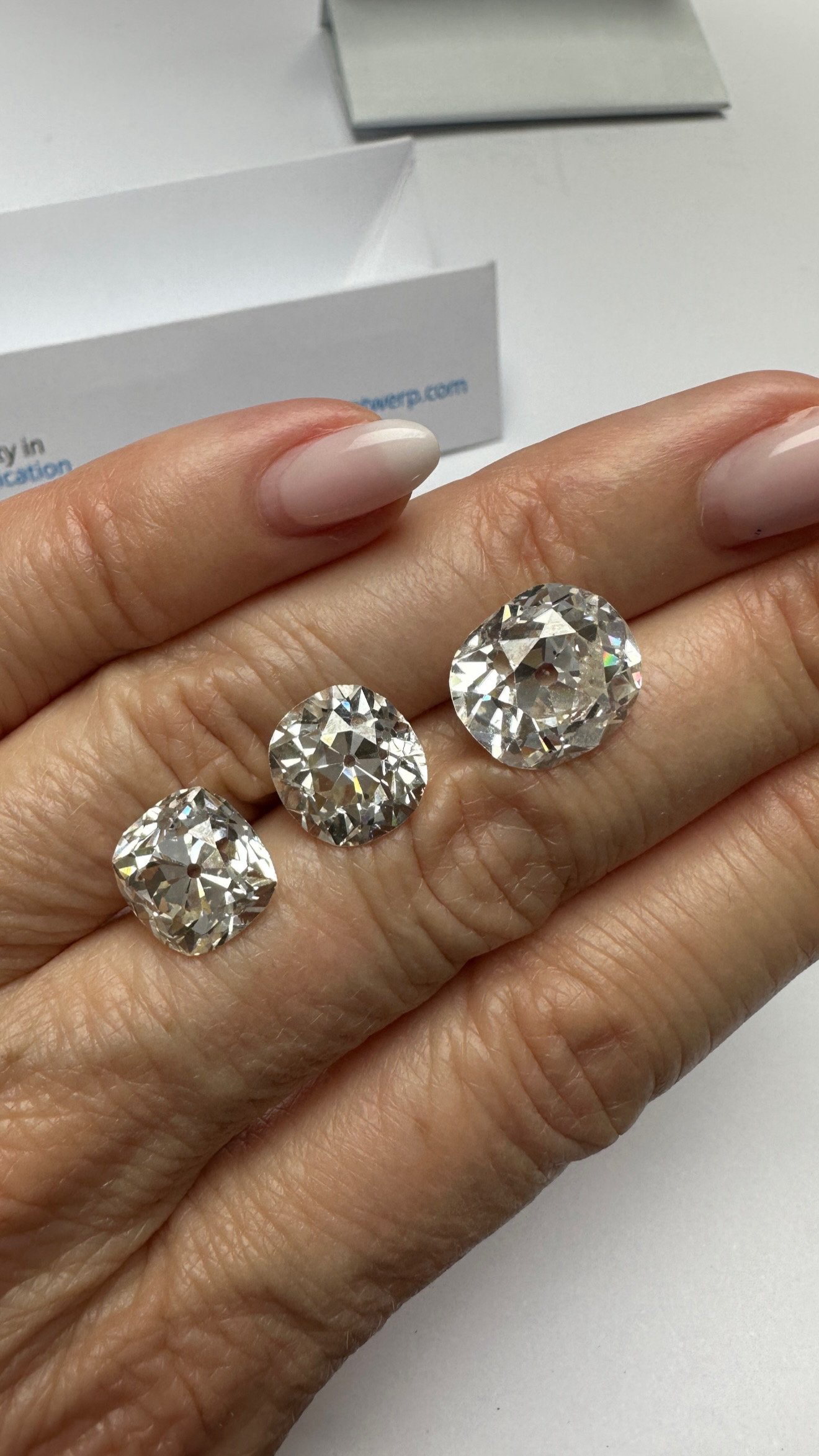 Three antique old-cut diamonds resting on a hand