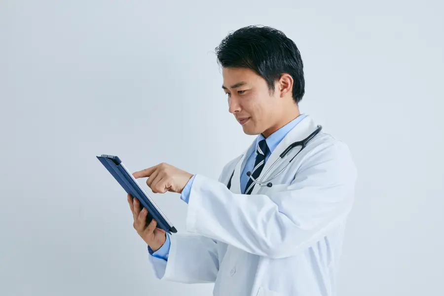 AI-powered medical administration captured as a white-coated doctor with a stethoscope taps through patient data on a tablet against a clean studio background.