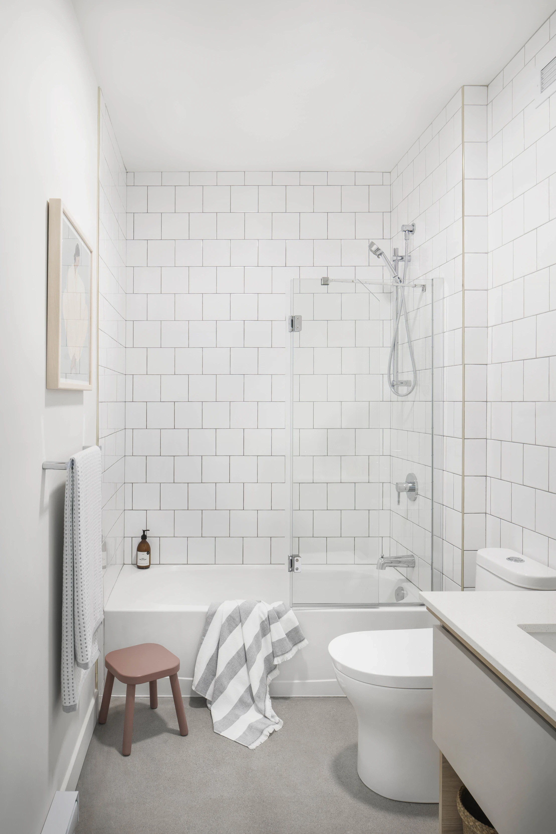 Minimalist bathroom at Le Petit Laurier, featuring white subway tiles, a glass shower partition, and soft natural light to enhance the sense of space.