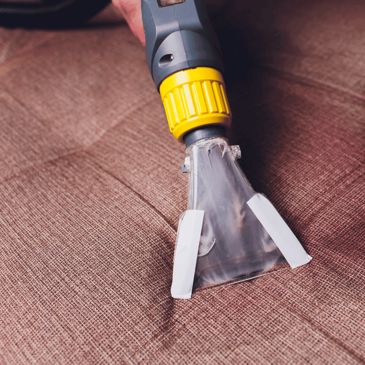 Professionelle Polsterreinigung mit Sprühextraktionsgerät auf braunem Sofa