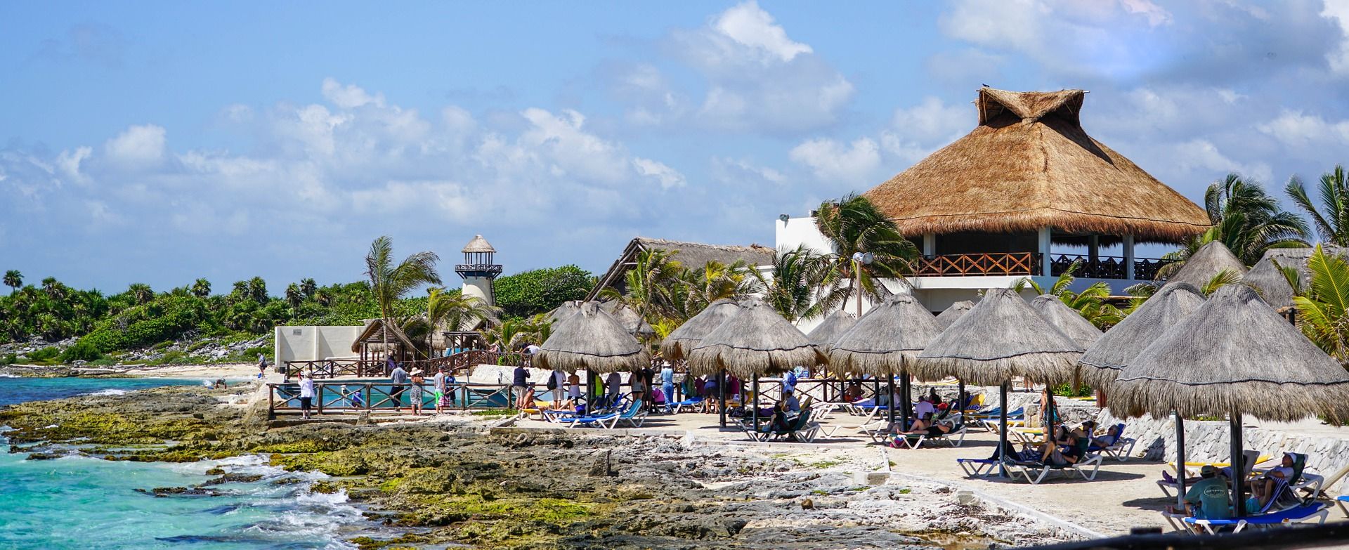 Thatched beach umbrellas and tourists at a beach in Cozumel