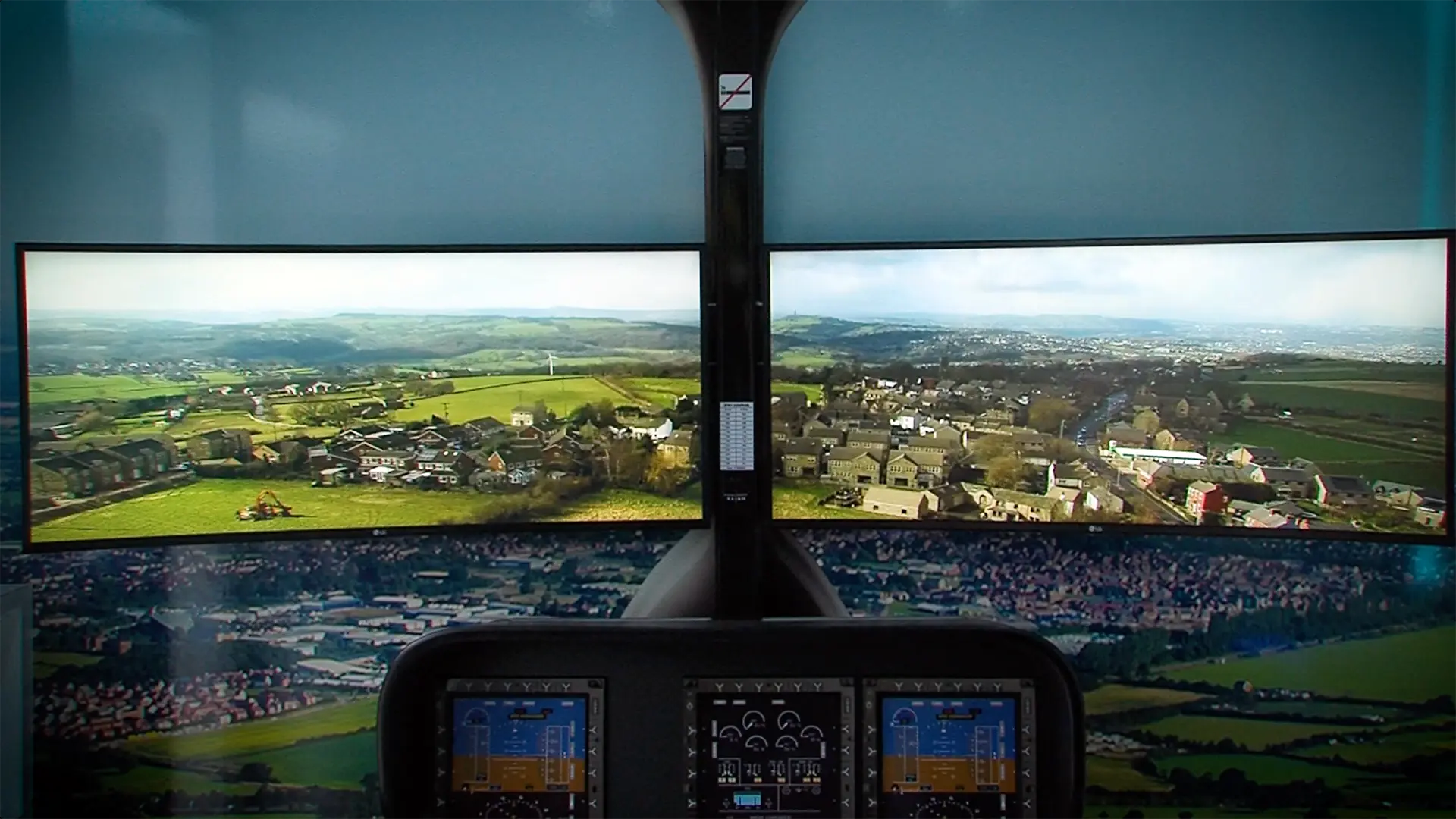 Dual curved screens inside an outreach vehicle displaying aerial views from a helicopter cockpit.