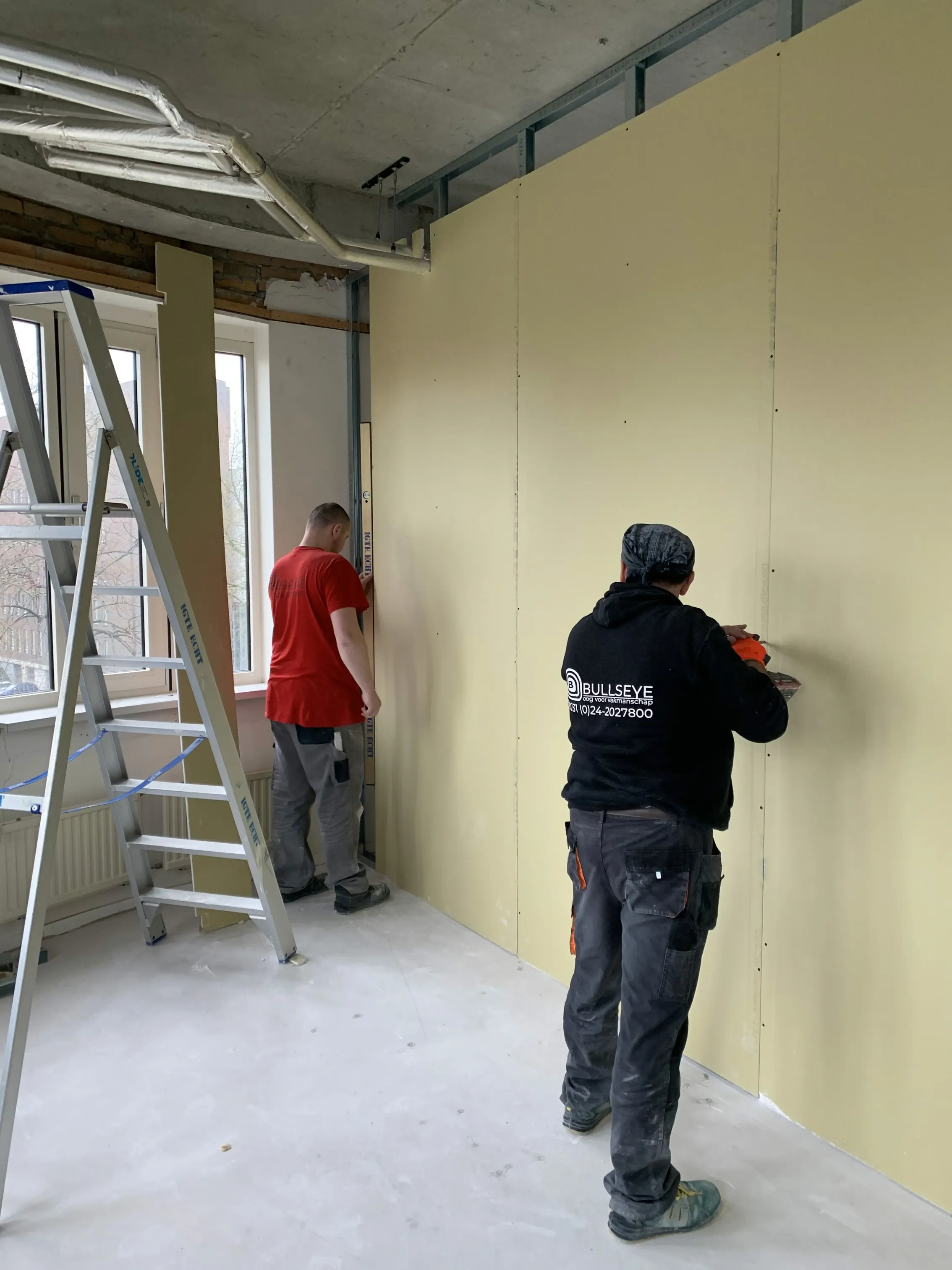 man in green and black plaid long sleeve shirt holding red and black cordless hand drill