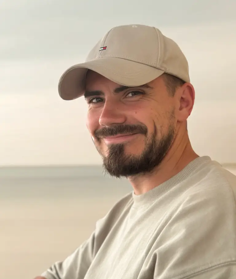 A smiling hadnsome young man, wearing a cap