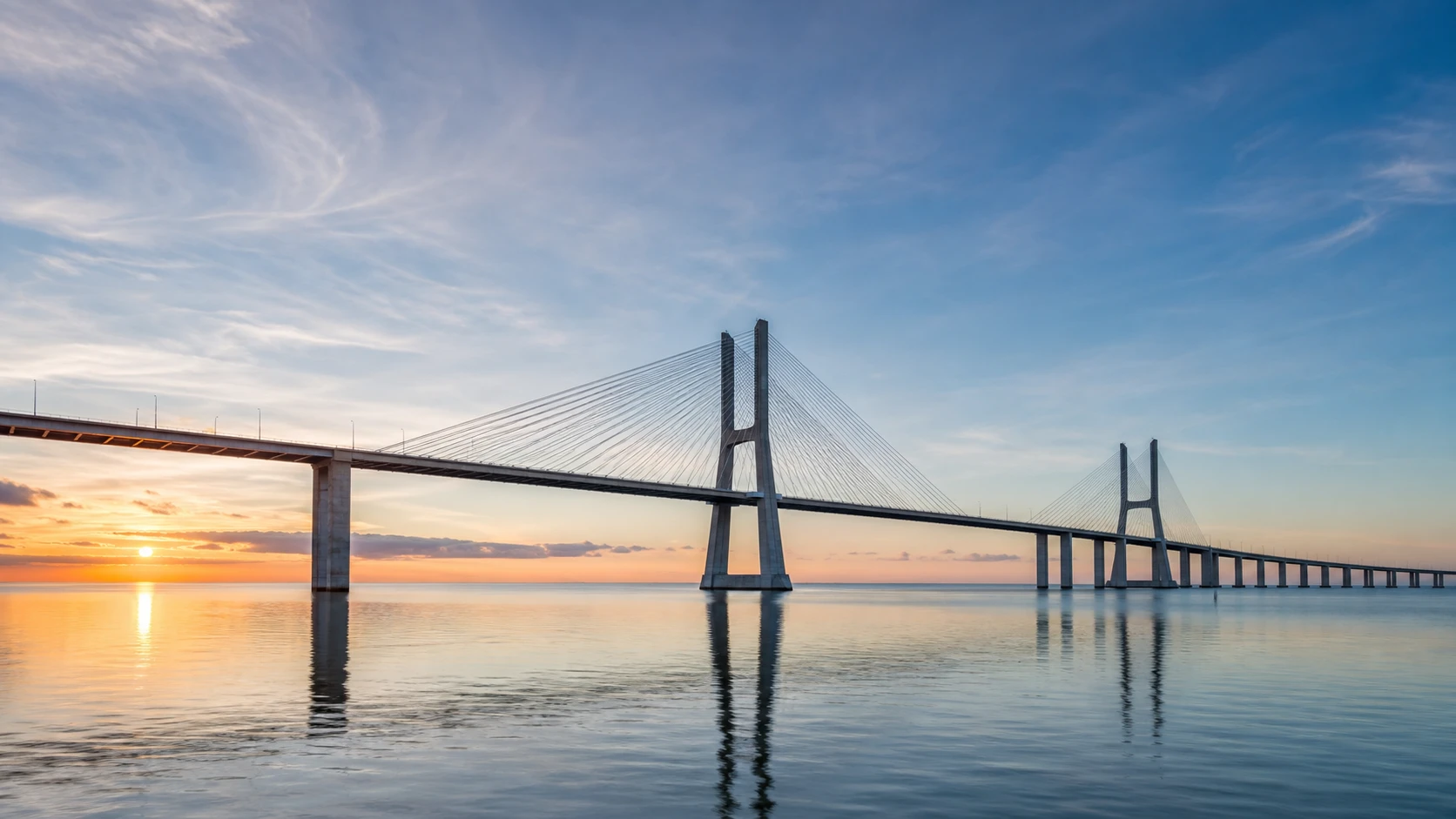 Modern European cable-stayed bridge above calm water at sunrise