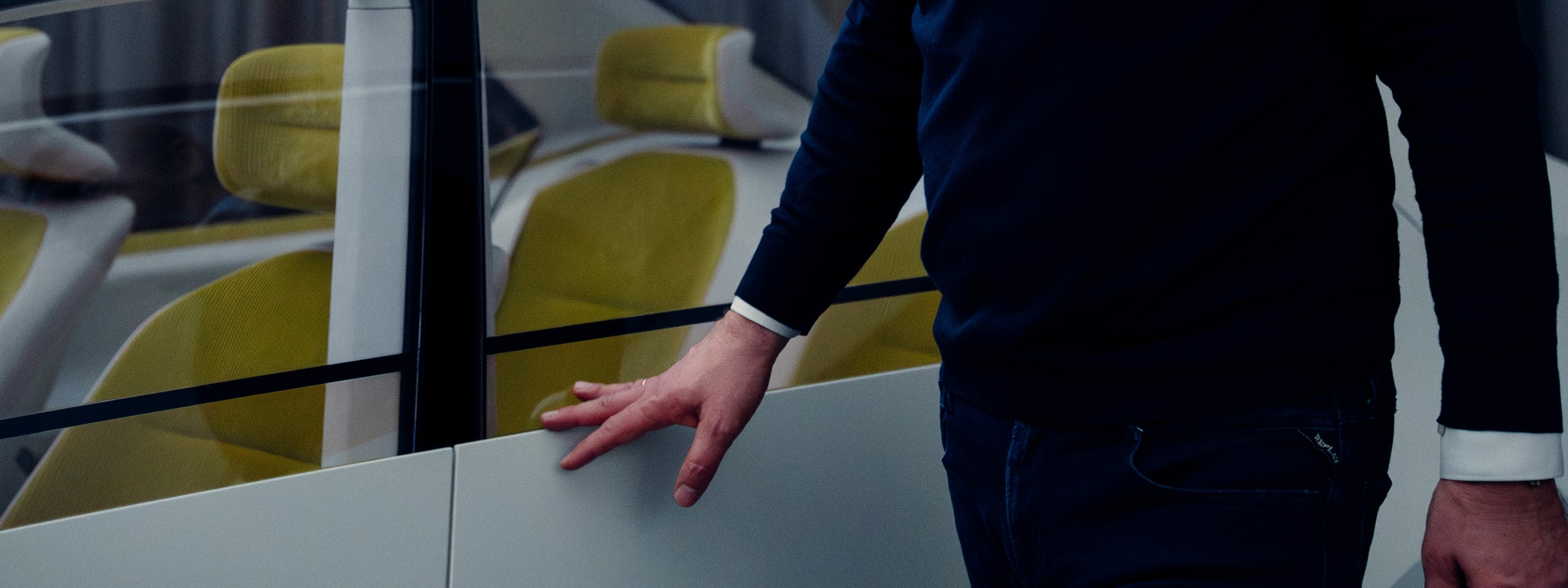 Close-up of a hand gliding over a car’s surface in a stylish blue-lit interior