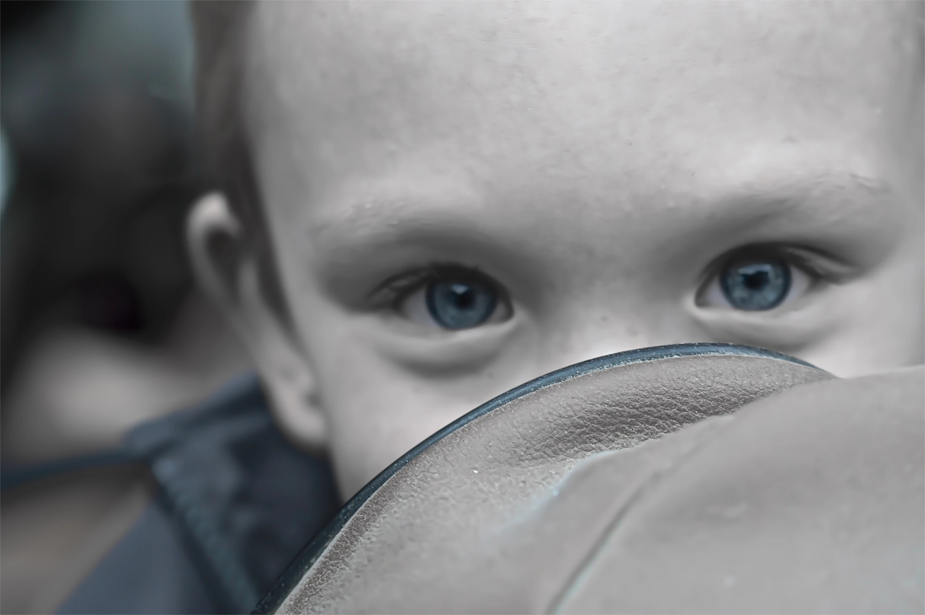 Nahaufnahme eines Kindes mit intensivem Blick durch eine Lupe, die Details vergrößert und scharf fokussiert. Die reduzierte Farbgebung und geringe Tiefenschärfe betonen Neugier, Präzision und den Akt des genauen Hinschauens – visuelle Metapher für analytische Expertise, Forschung und Detailgenauigkeit.