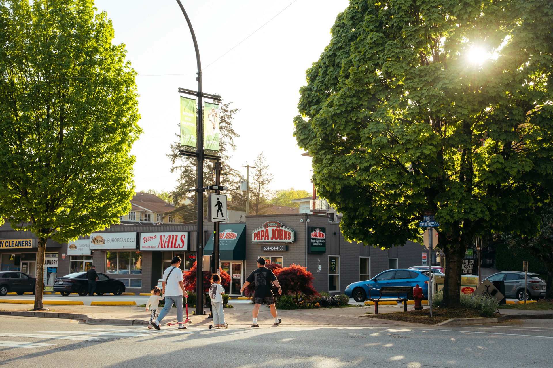 Close-up of an athlete's feet wearing white track spikes, standing next to blue starting blocks on a red track.
