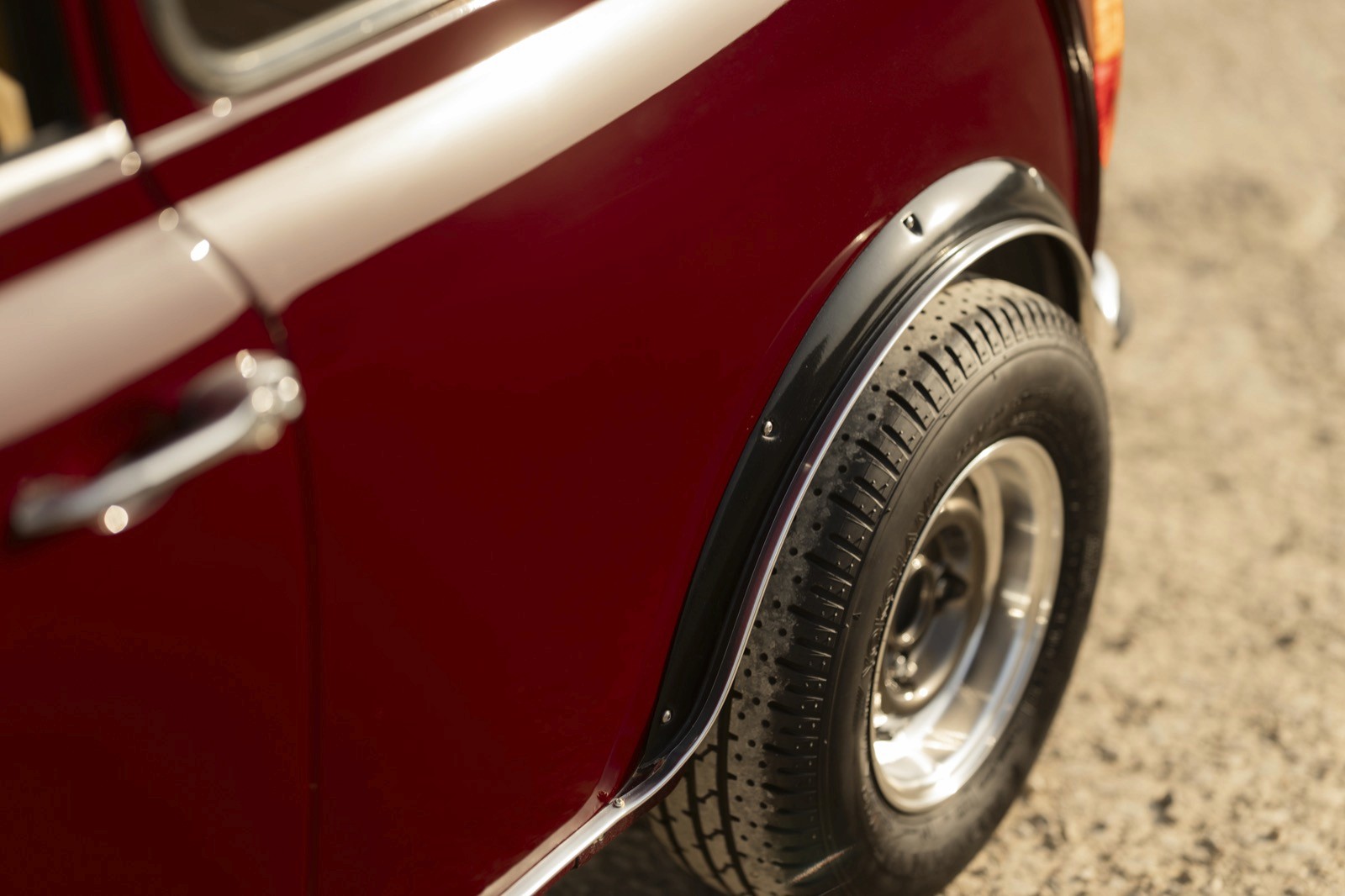 Close-up view of the rear wheel and fender of a red car, showcasing its shiny chrome details.