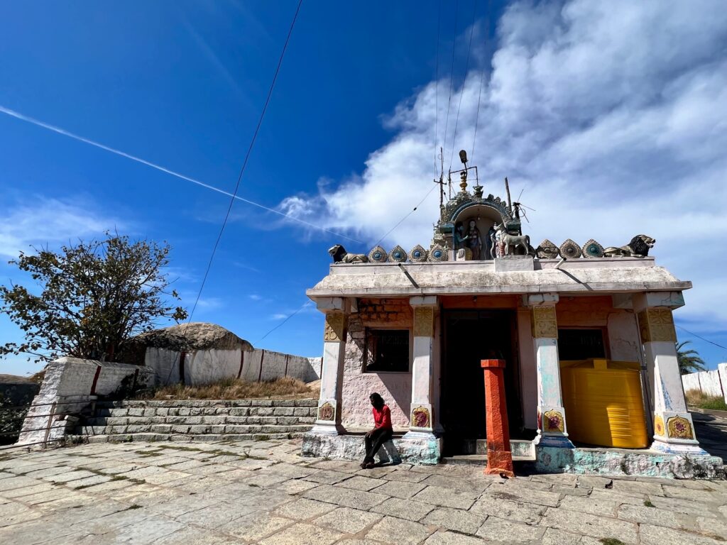 Sita devi temple at the summit with a man sitting outside the temple near the stairs