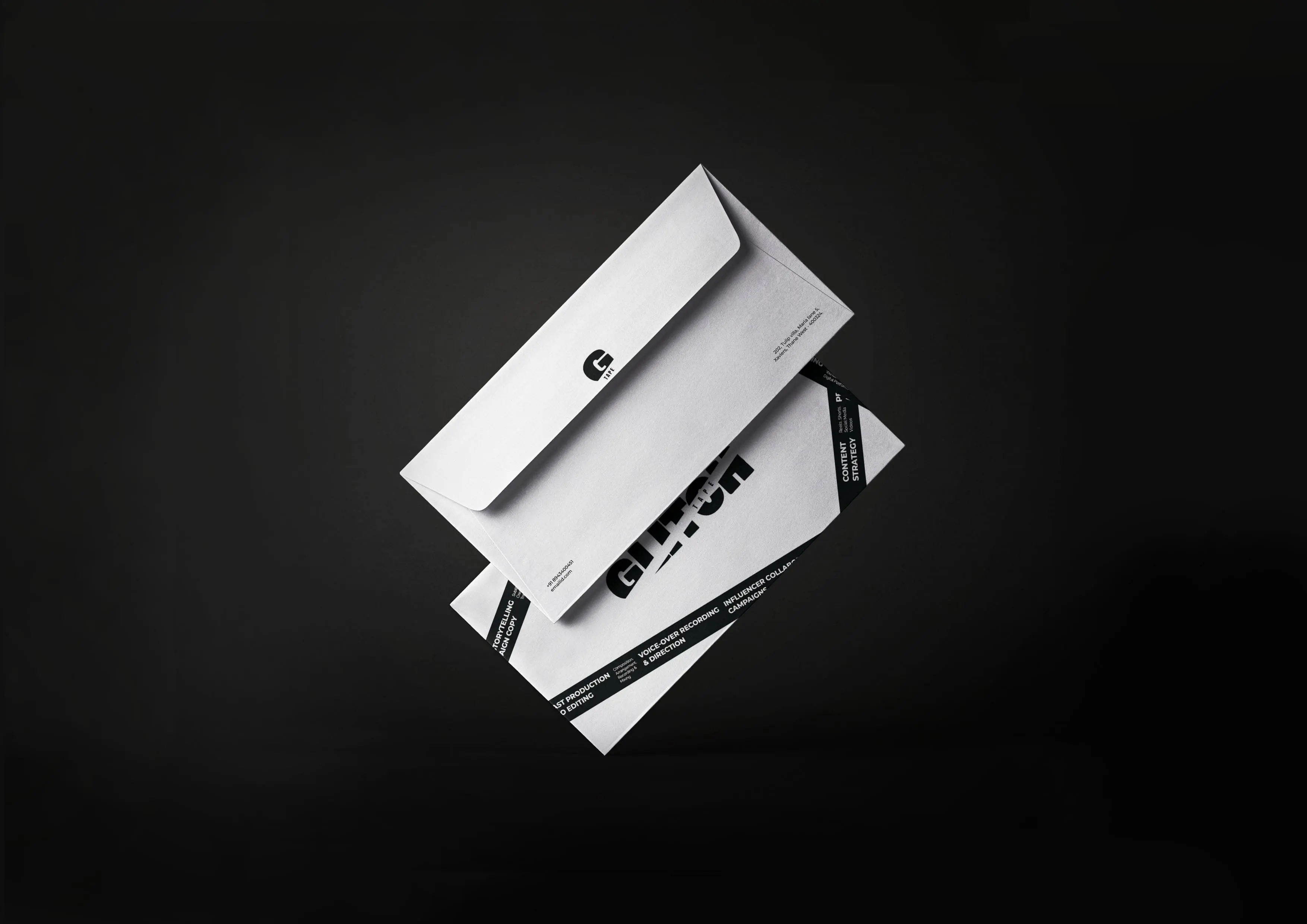 Overhead view of a white envelope and branded cards arranged diagonally on a black background, creating a sleek, minimalist, professional mood.