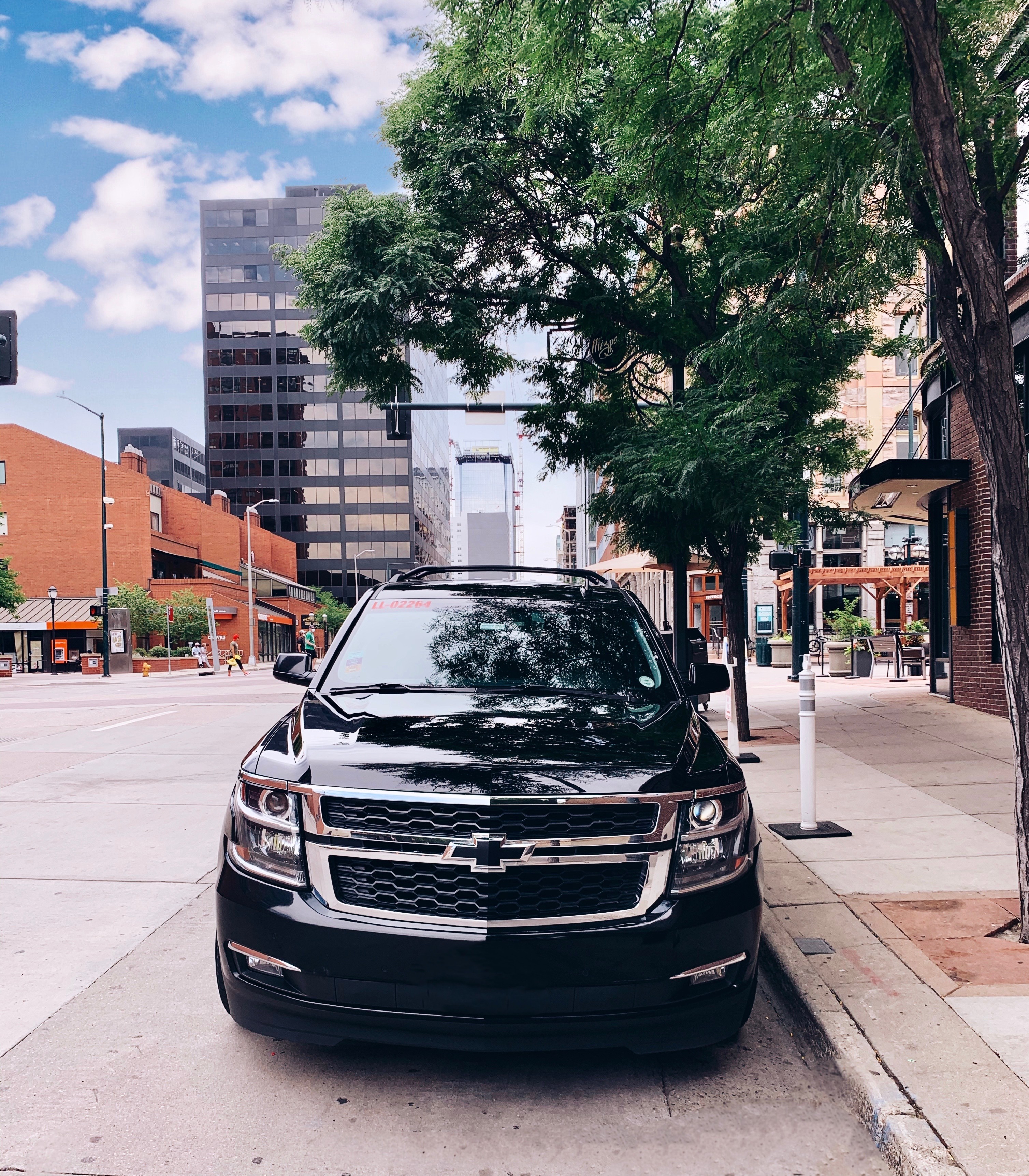 A sleek black Chevrolet SUV from Avo Limo Express parked on a stylish downtown Denver street, highlighting luxury private car service.