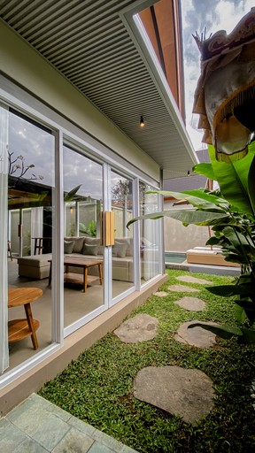 Smiling young man with short hair poses against a dark background, wearing a green button-up shirt.
