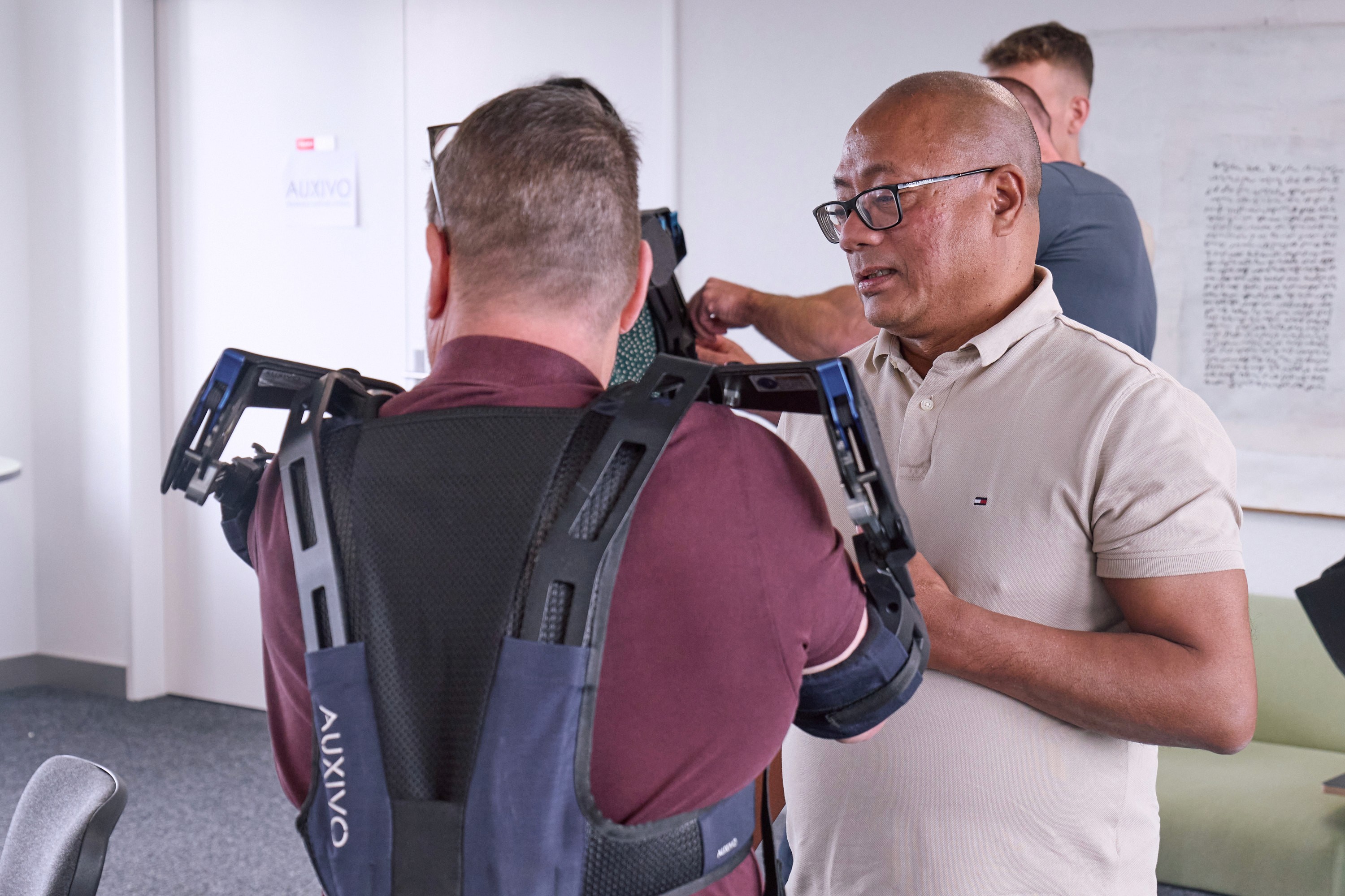 Ajustement d’un exosquelette industriel Auxivo lors d’une formation sur la prévention des troubles musculosquelettiques en milieu de travail.