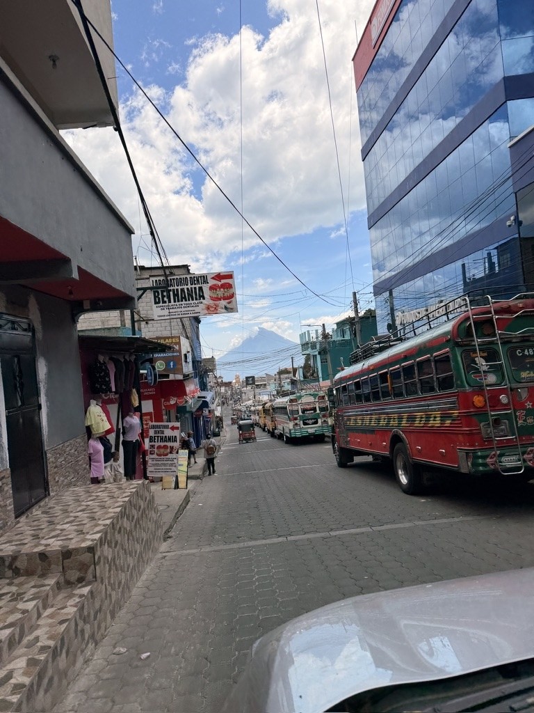 Chicken buses and a tuk-tuk filling a narrow street in Sololá, Guatemala.