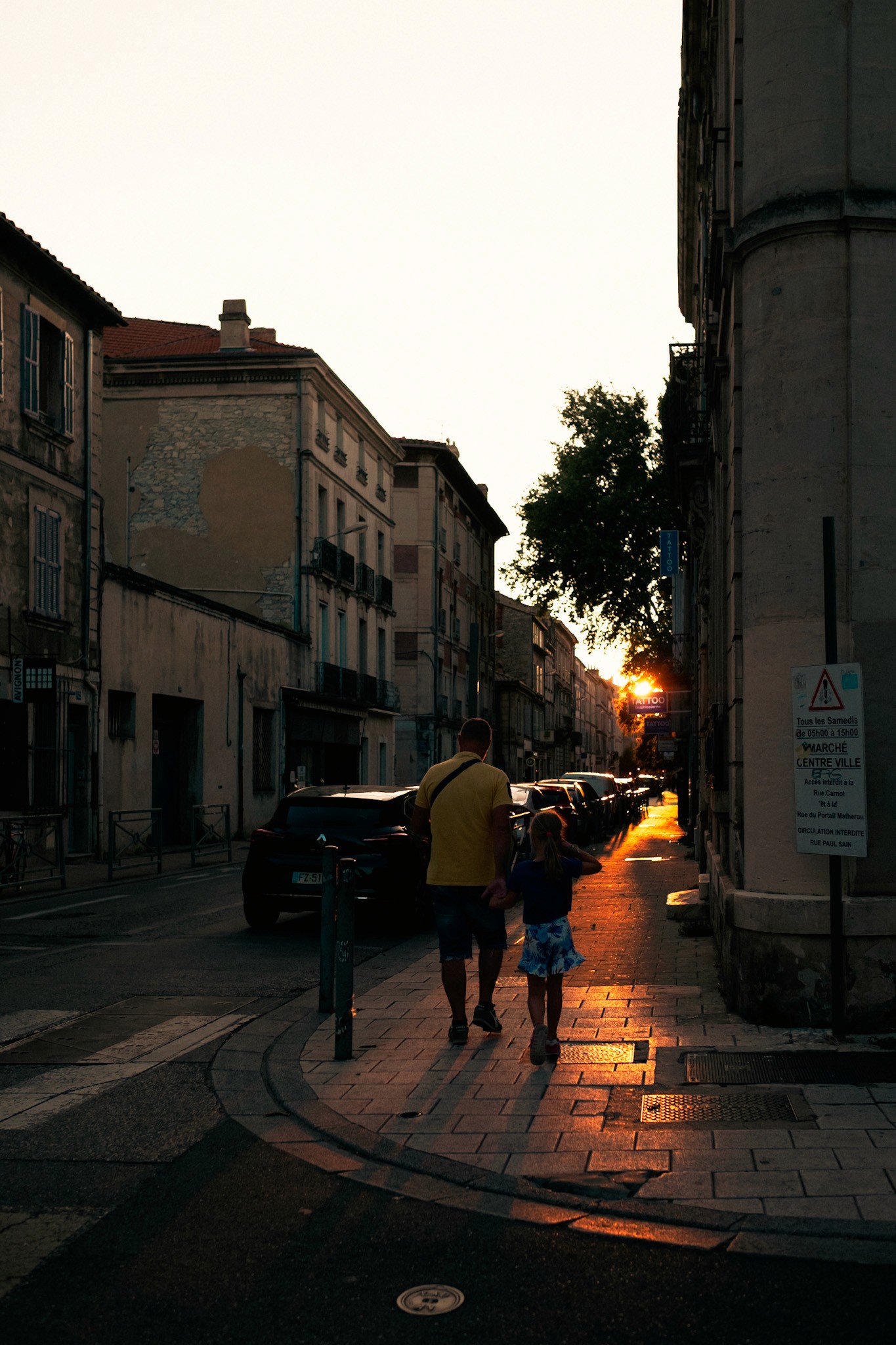 Two people walking on the street at sunset