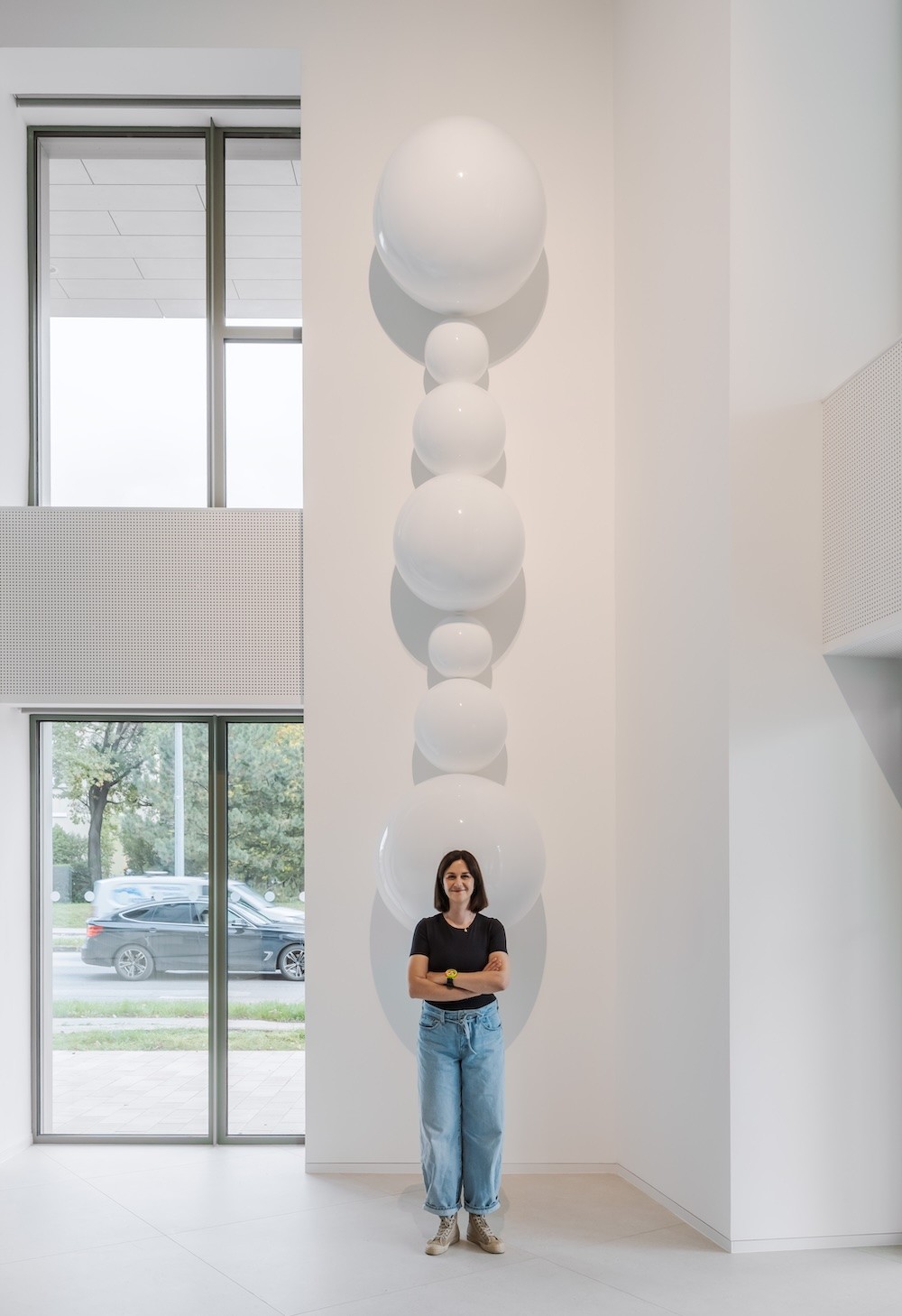 žltý smiley objekt visiaci v priestore pred človekom – výstava Niny A. Šoškovej