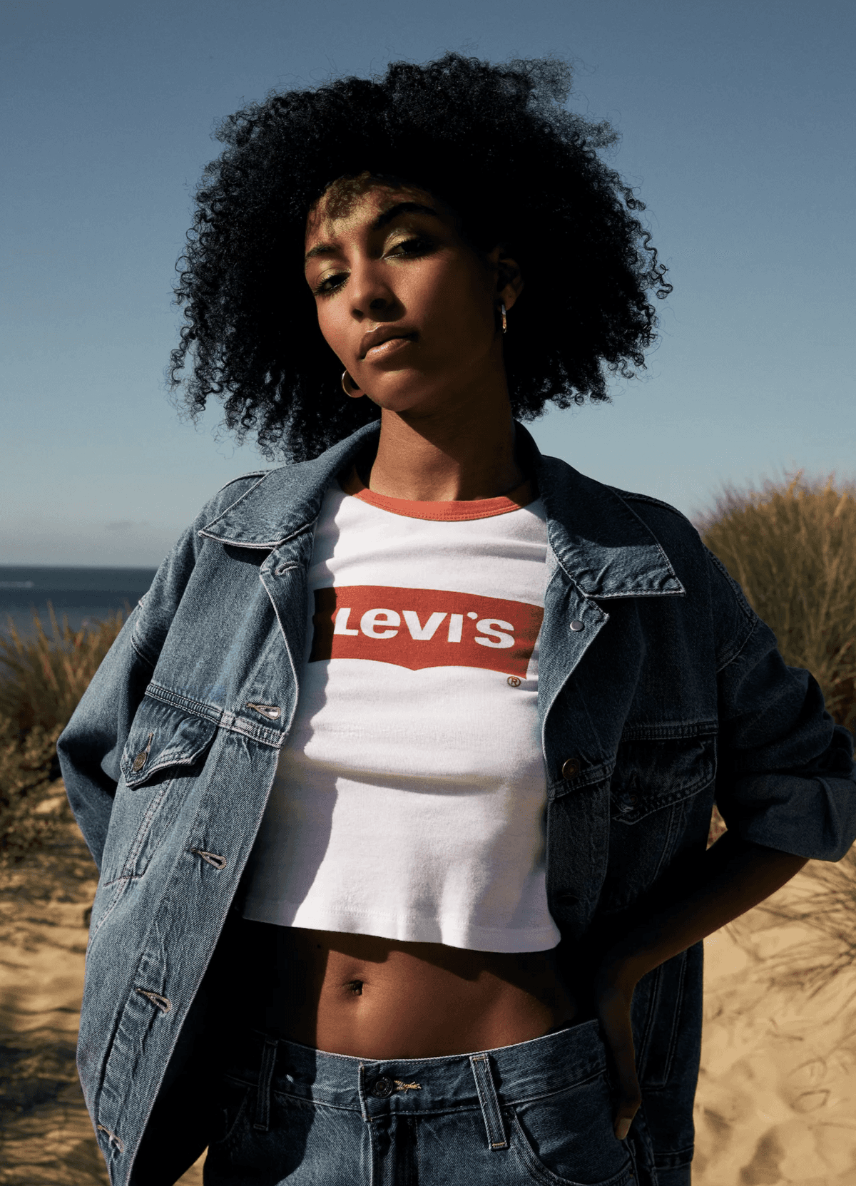 Model in a denim jacket in golden desert light for a lifestyle fashion campaign, by editorial makeup artist Em-J