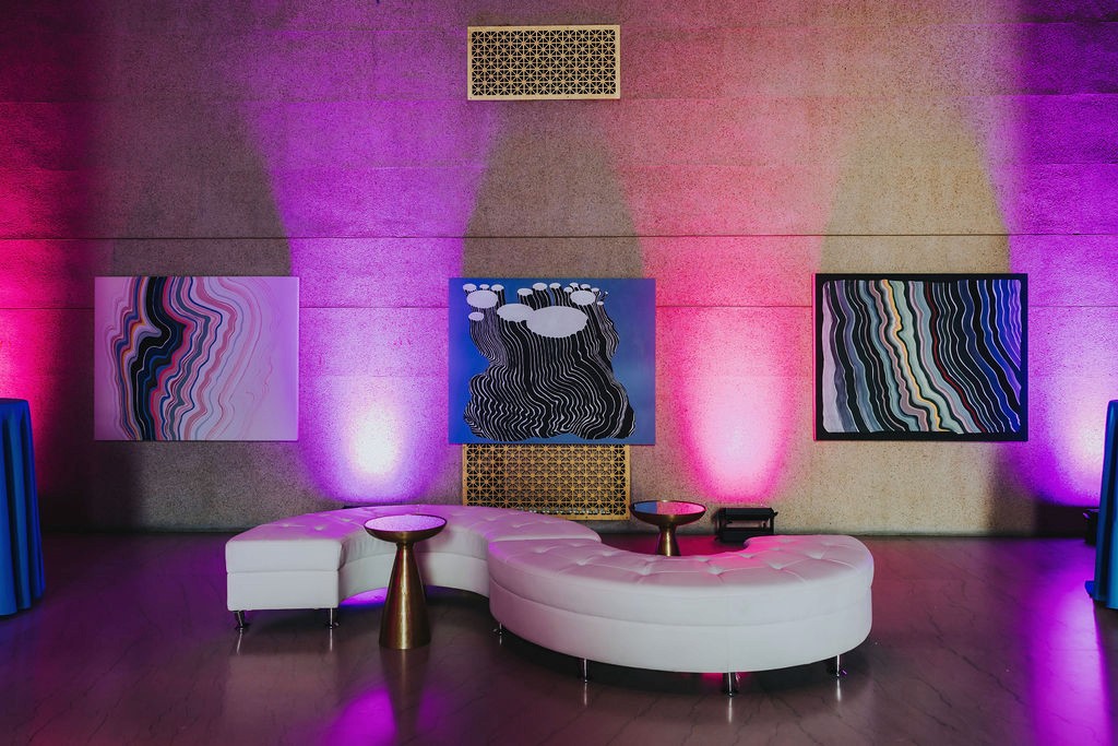 Lounge with white circular sofa and art panels under pink uplighting at the Bright Nights fundraiser, Nashville's Parthenon — event production by UpLight Technologies