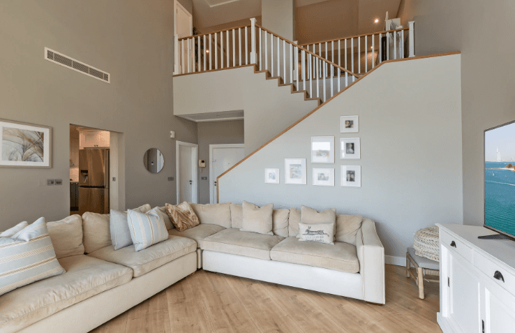 A living room in Shoreline Apartments featuring a couch, television, and stairs leading to another level.