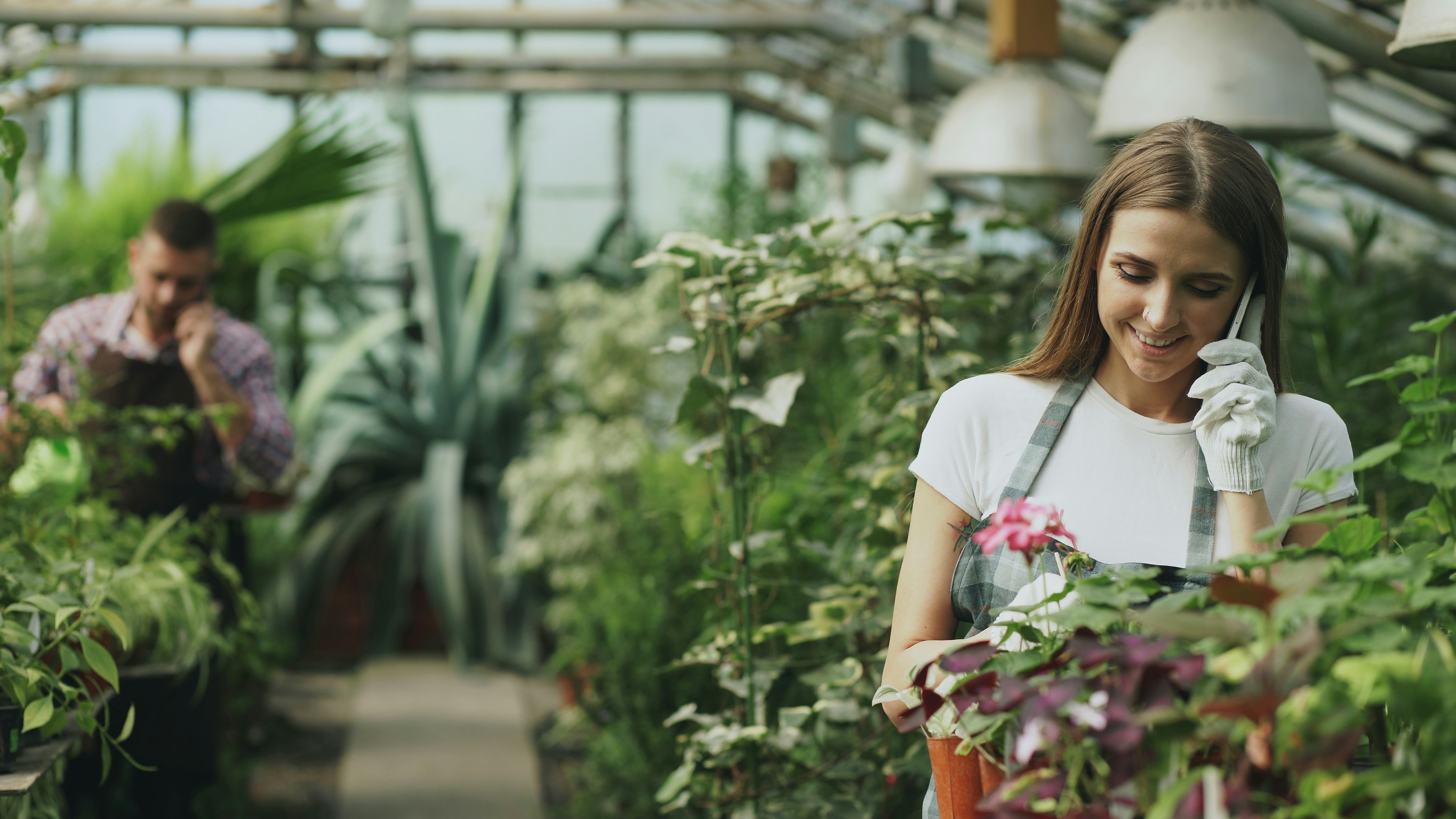 Woman talking on phone in greenhouse with plants