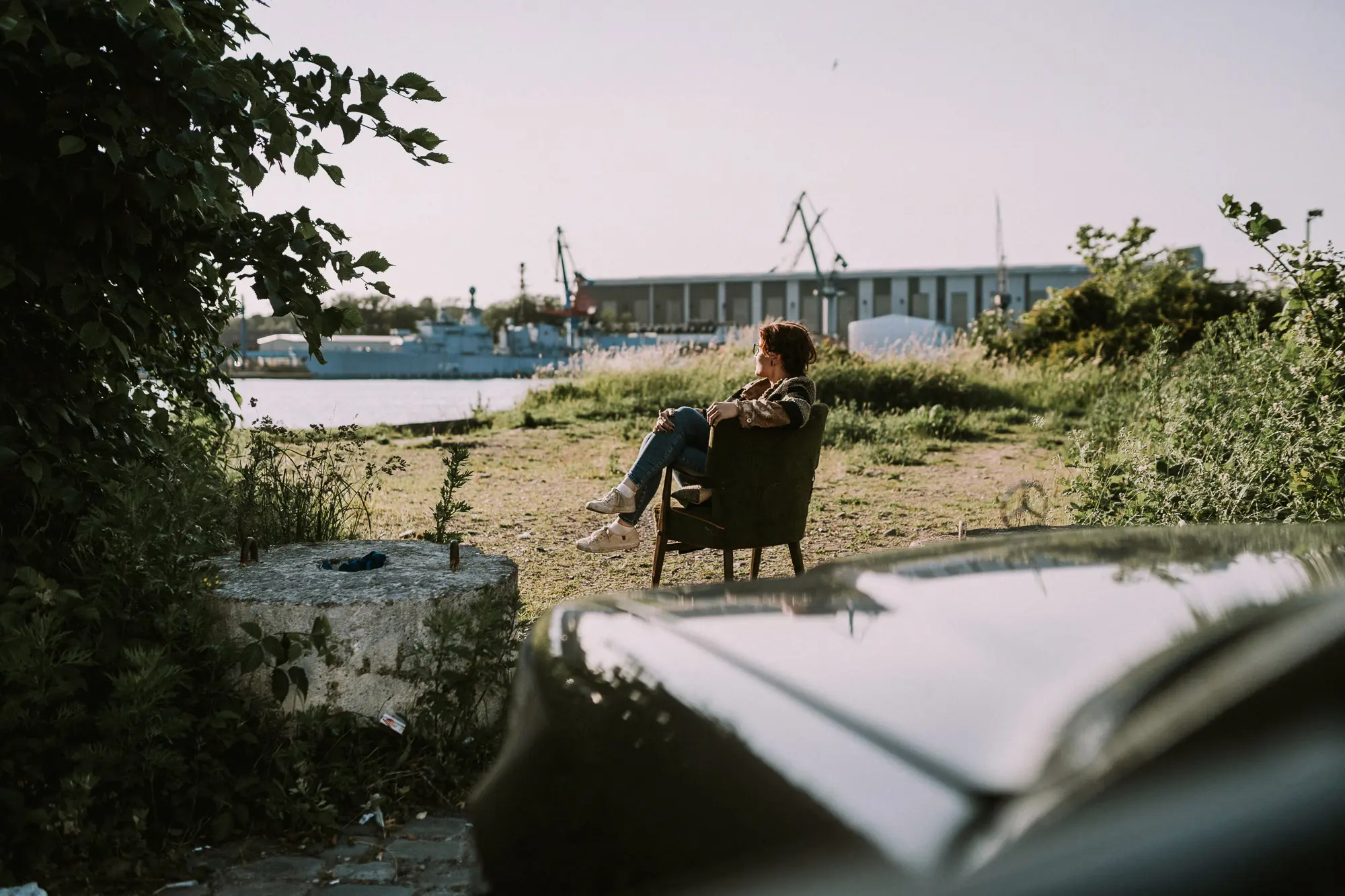 Frau sitzt entspannt am Hafen und blickt in die Ferne, Symbolbild für Visionen, Strategie und langfristige Unternehmensentwicklung