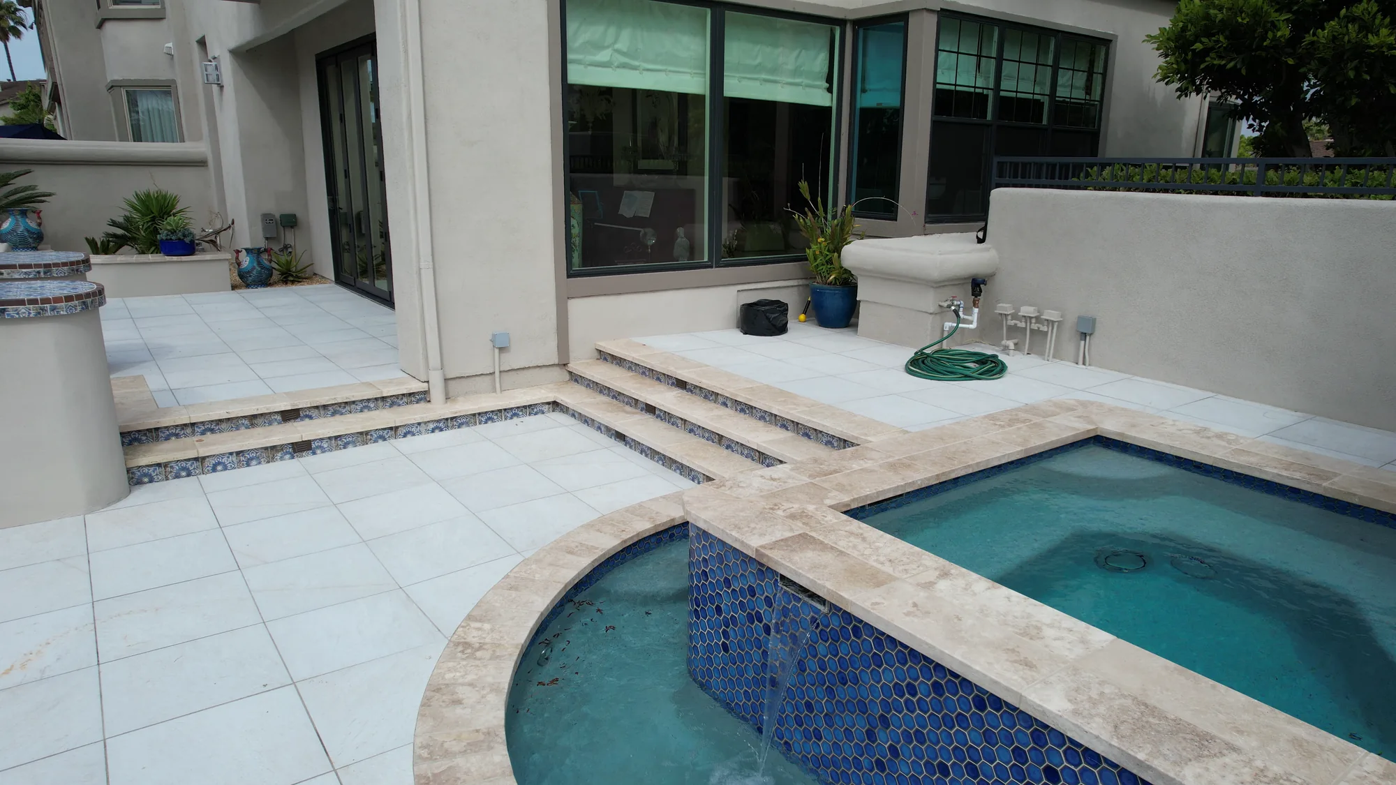 Raised tiled spa beside a curved swimming pool and pale paved terrace.