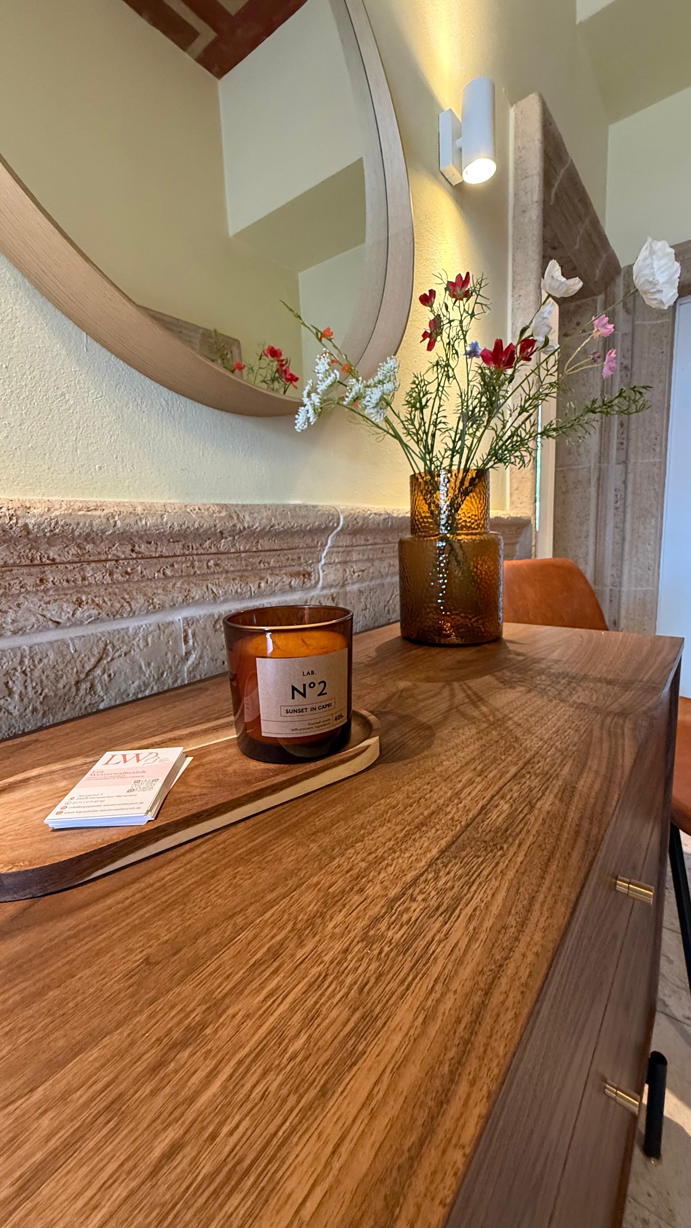 Empfangstresen mit Visitenkarten, Duftkerze und frischen Blumen in der Praxis Lea Westerwalbesloh