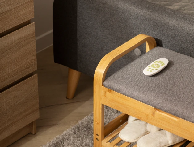 Cozy bedroom corner with a wooden bench, gray cushion, and slippers underneath.