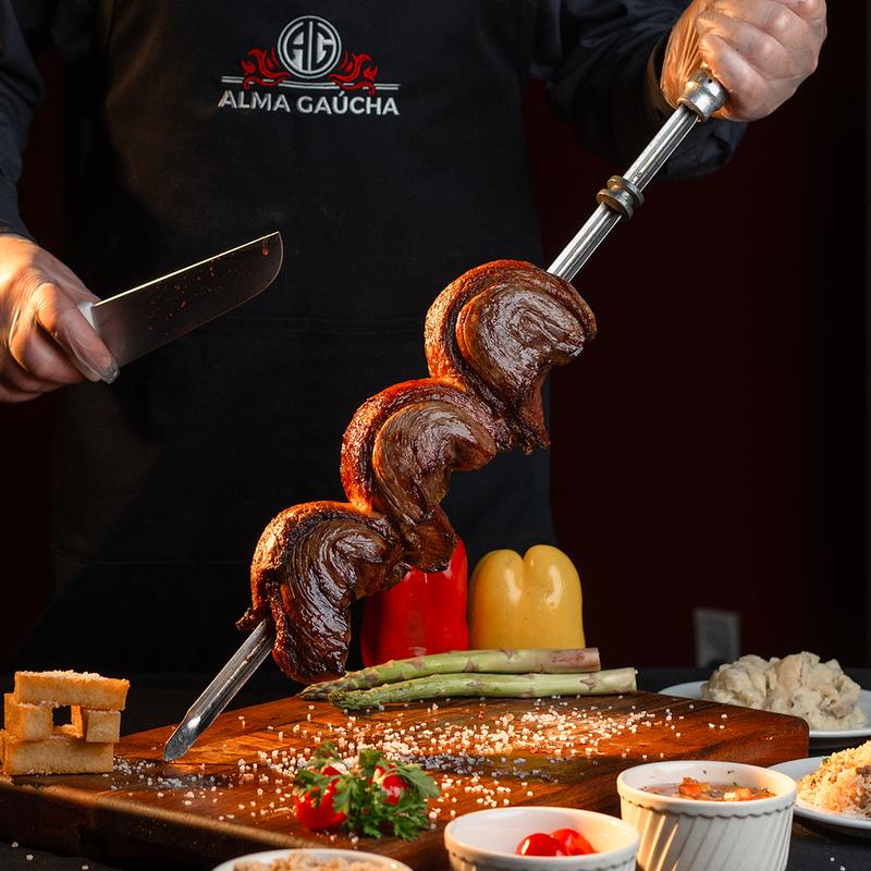 A chef carving fire-roasted meat at Alma Gaucha