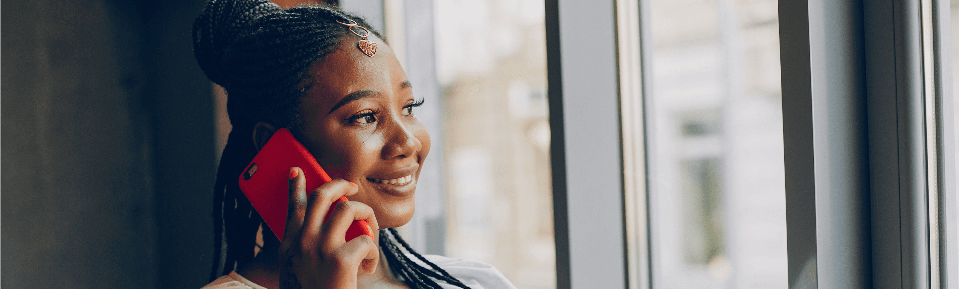 A picture of a lady making a phone call, smiling and looking out the window